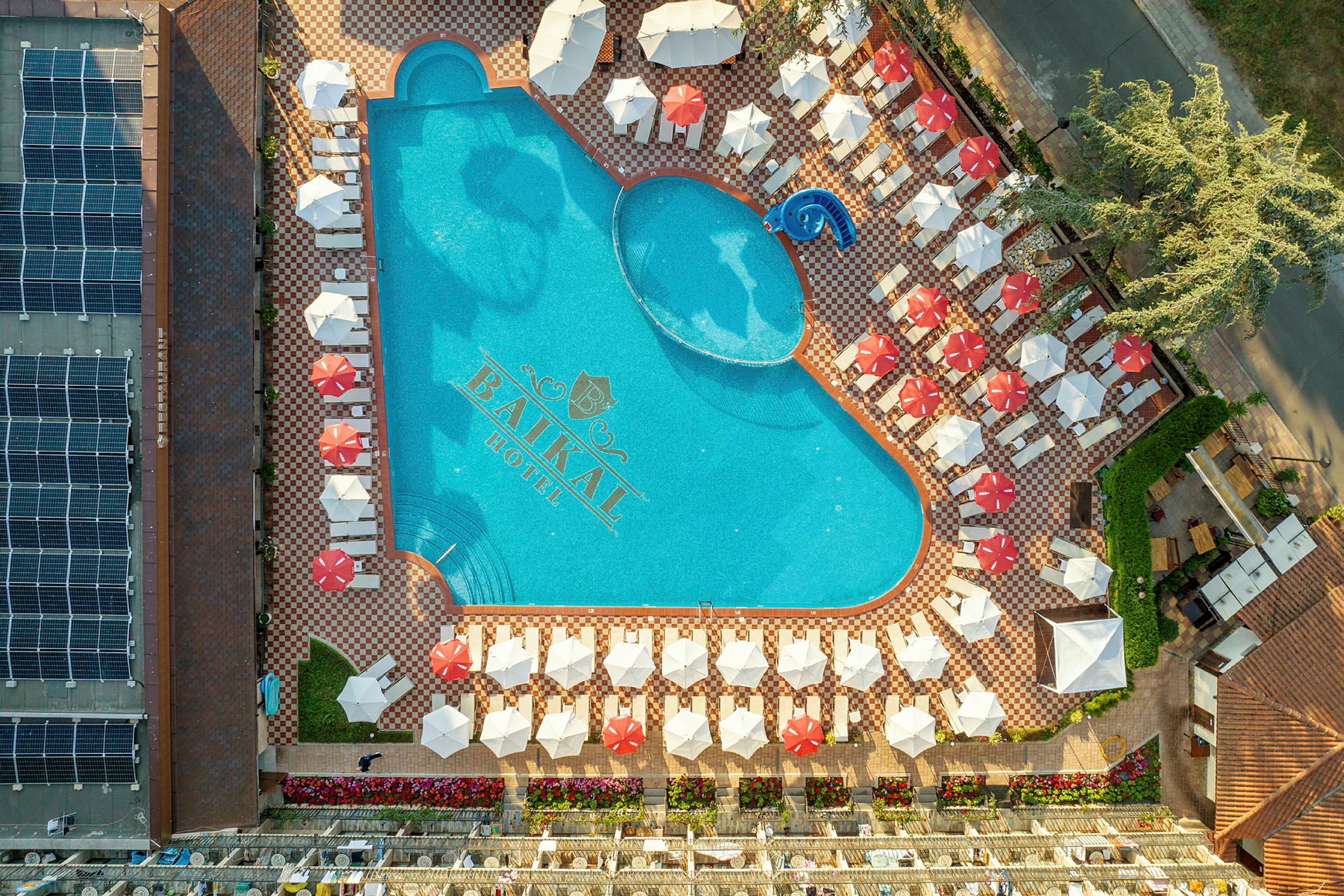 En flygbild av en utomhuspool omgiven av solstolar och parasoller vid Baikal Hotel. (AI-genererad text)