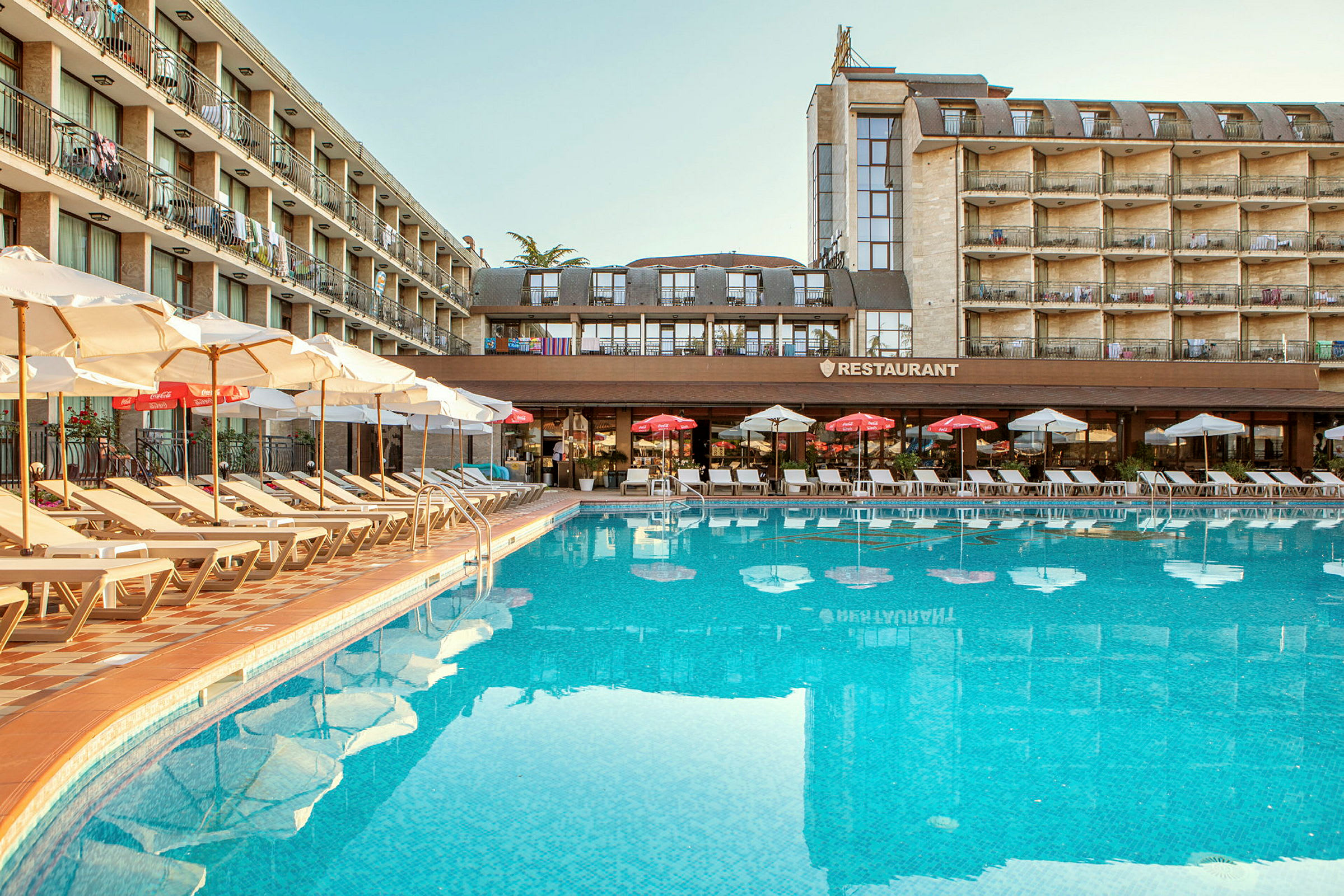 Utomhuspool vid ett hotell med solsängar och parasoller. (AI-genererad text)