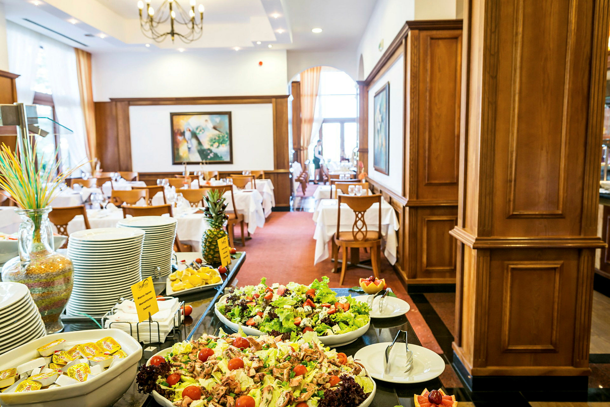 Buffébord med sallad, frukt och porslin i en elegant inredd restaurang. (AI-genererad text)