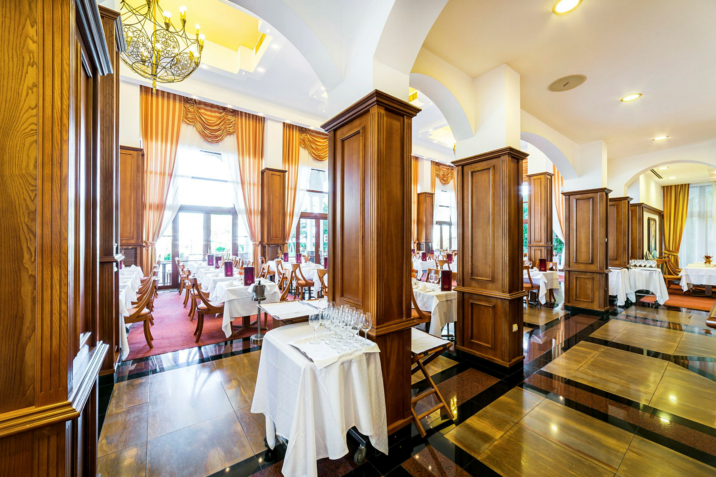 En elegant restaurang med dukade bord, mörka trägolv och stora fönster med gardiner. (AI-genererad text)