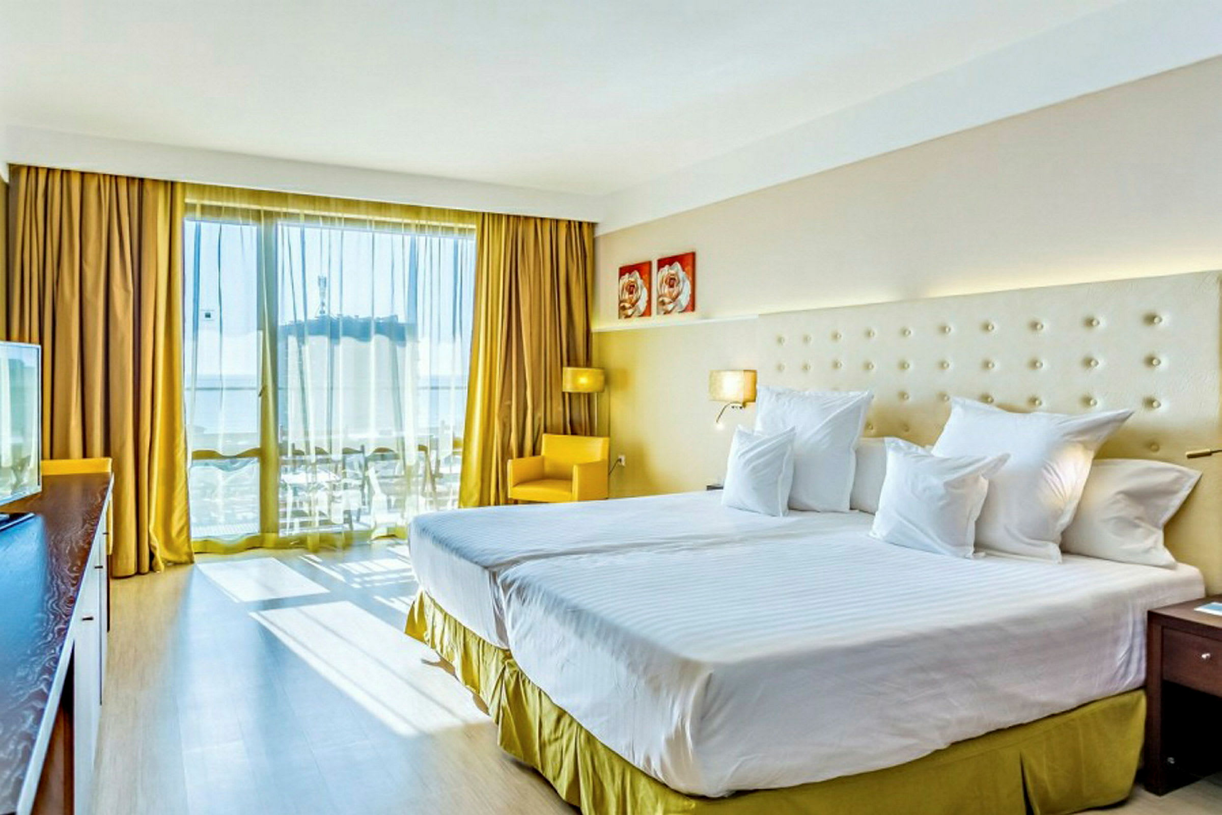 Bild på ett hotellrum med två sängar, ljus inredning, och stora fönster med långa gardiner. (AI-genererad text)