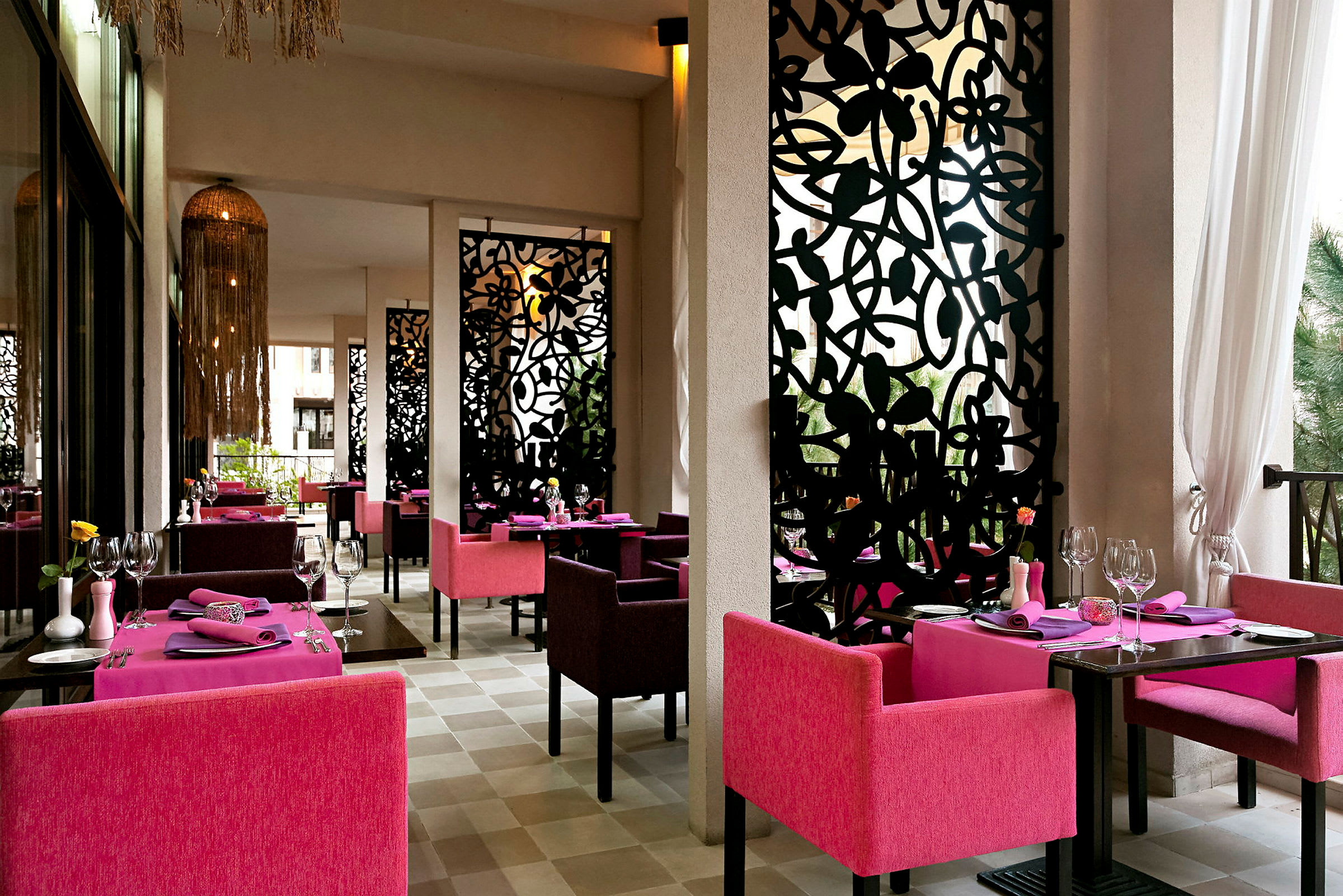 En restaurang med färgglada rosa fåtöljer och invändiga dekorativa svarta paneler. (AI-genererad text)