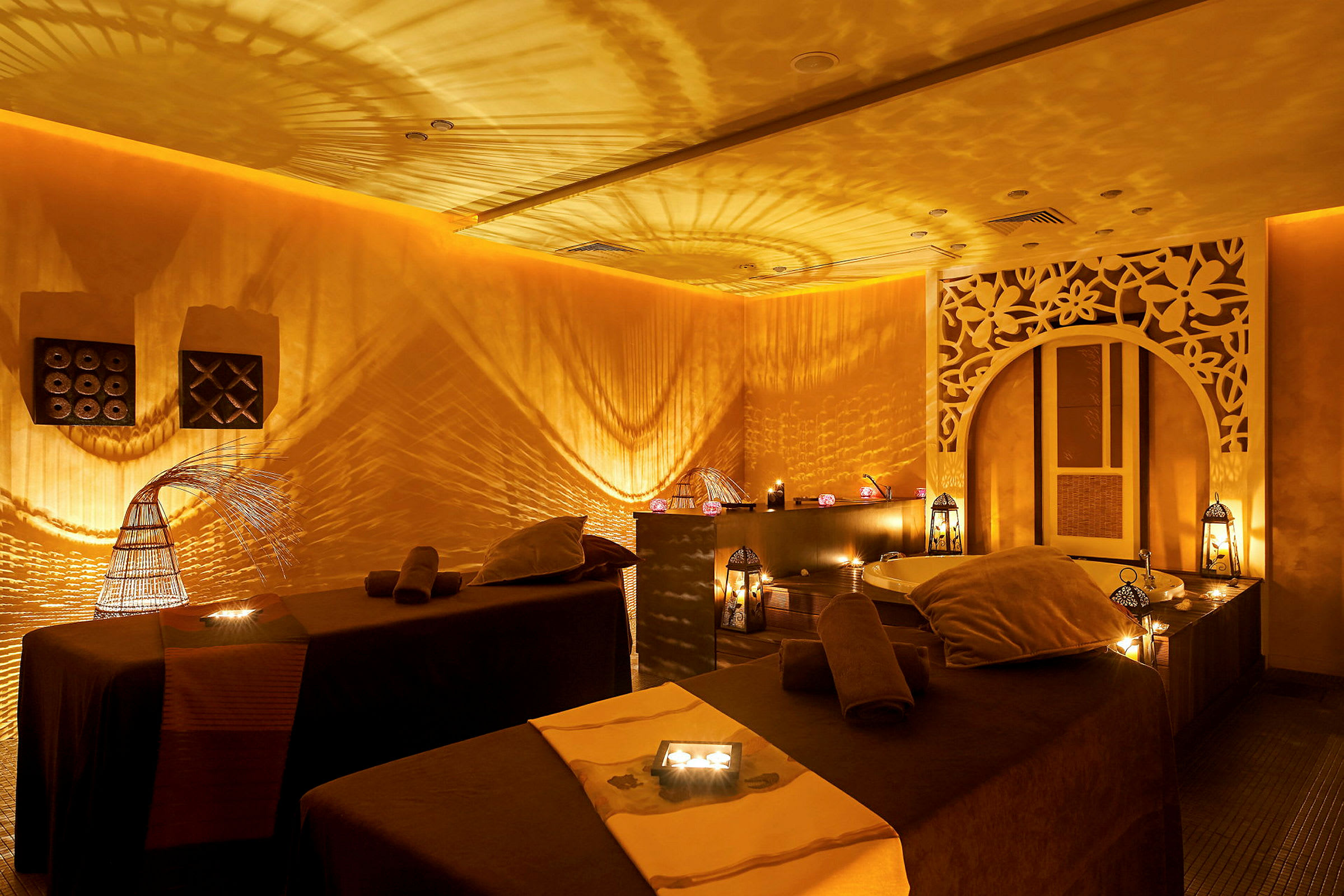 Ett stämningsfullt spa-rum med mjuk belysning, två massagebänkar och dekorativa lyktor. (AI-genererad text)