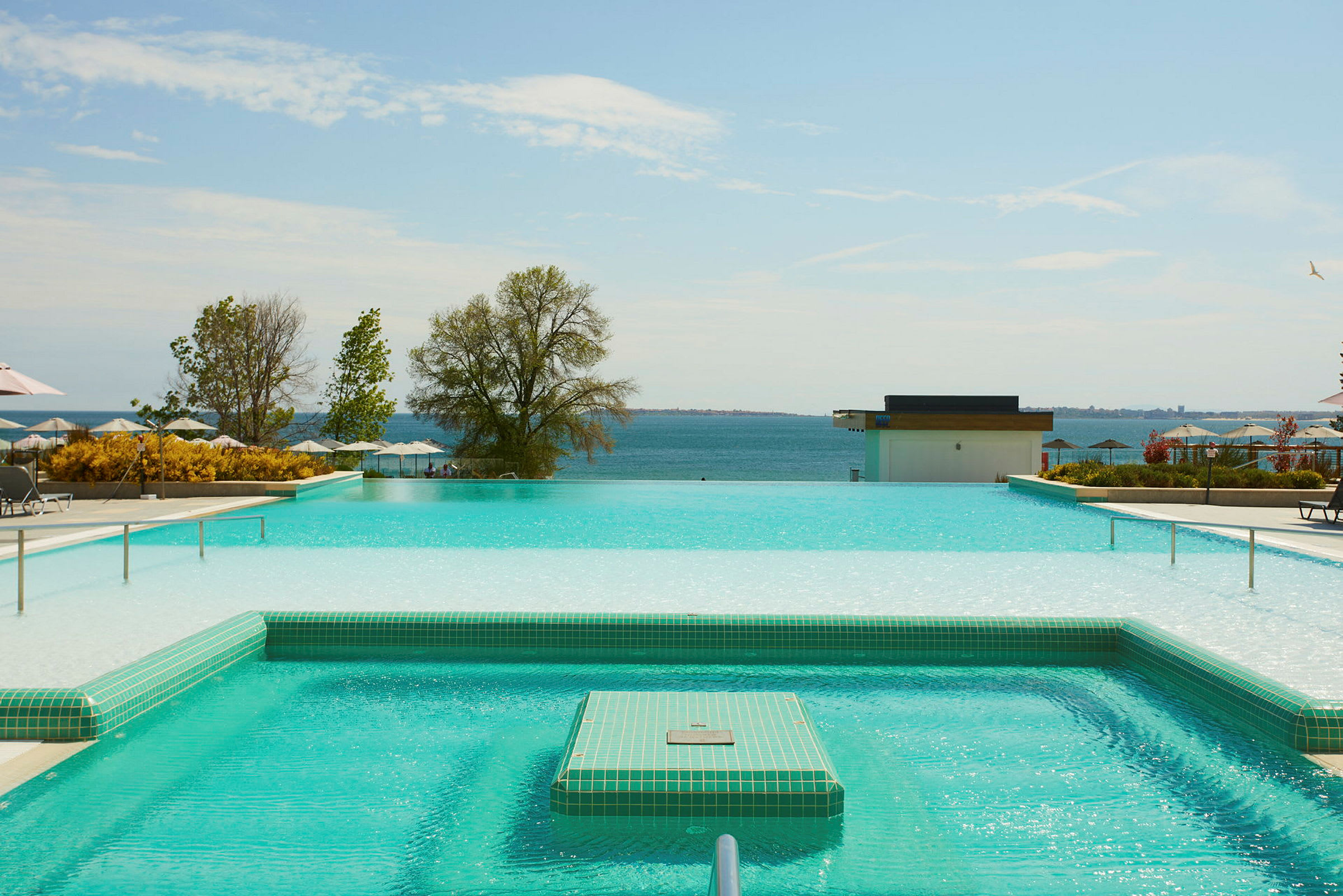 En infinitypool med utsikt över havet och omgivande grönska. (AI-genererad text)