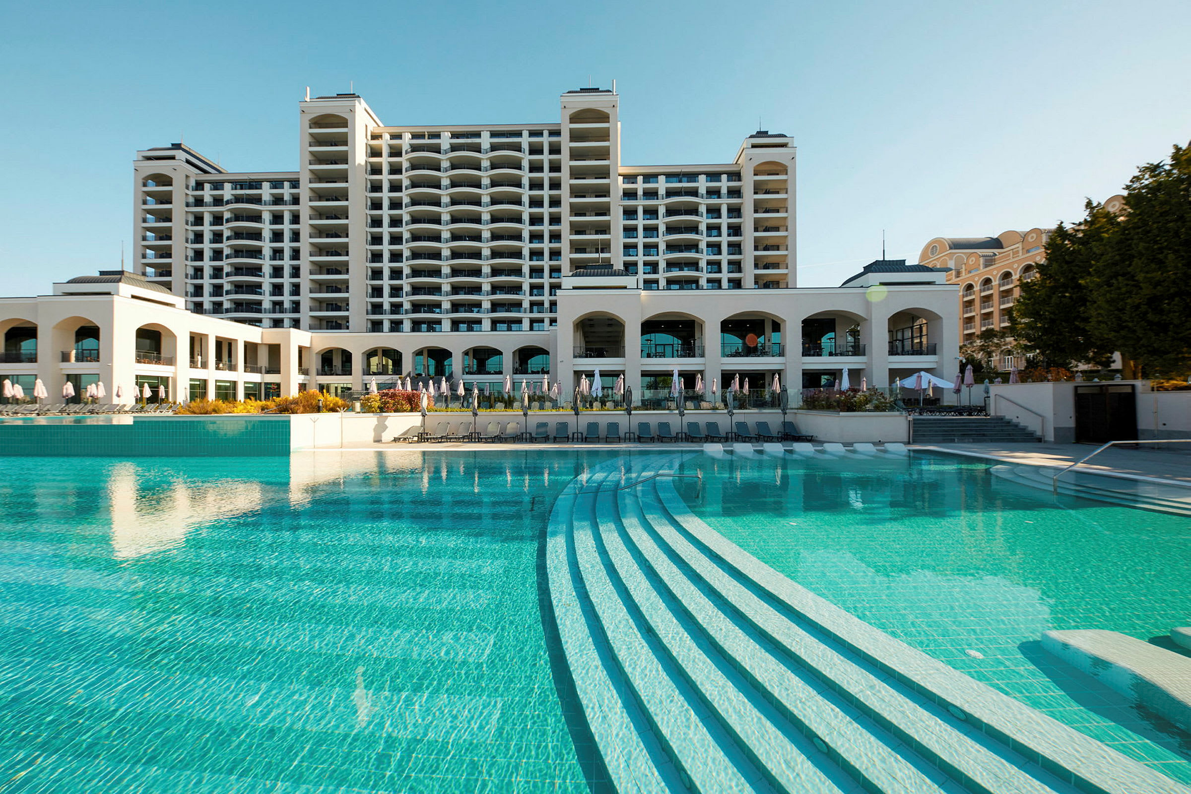 Hotellbyggnad vid en stor utomhuspool. (AI-genererad text)