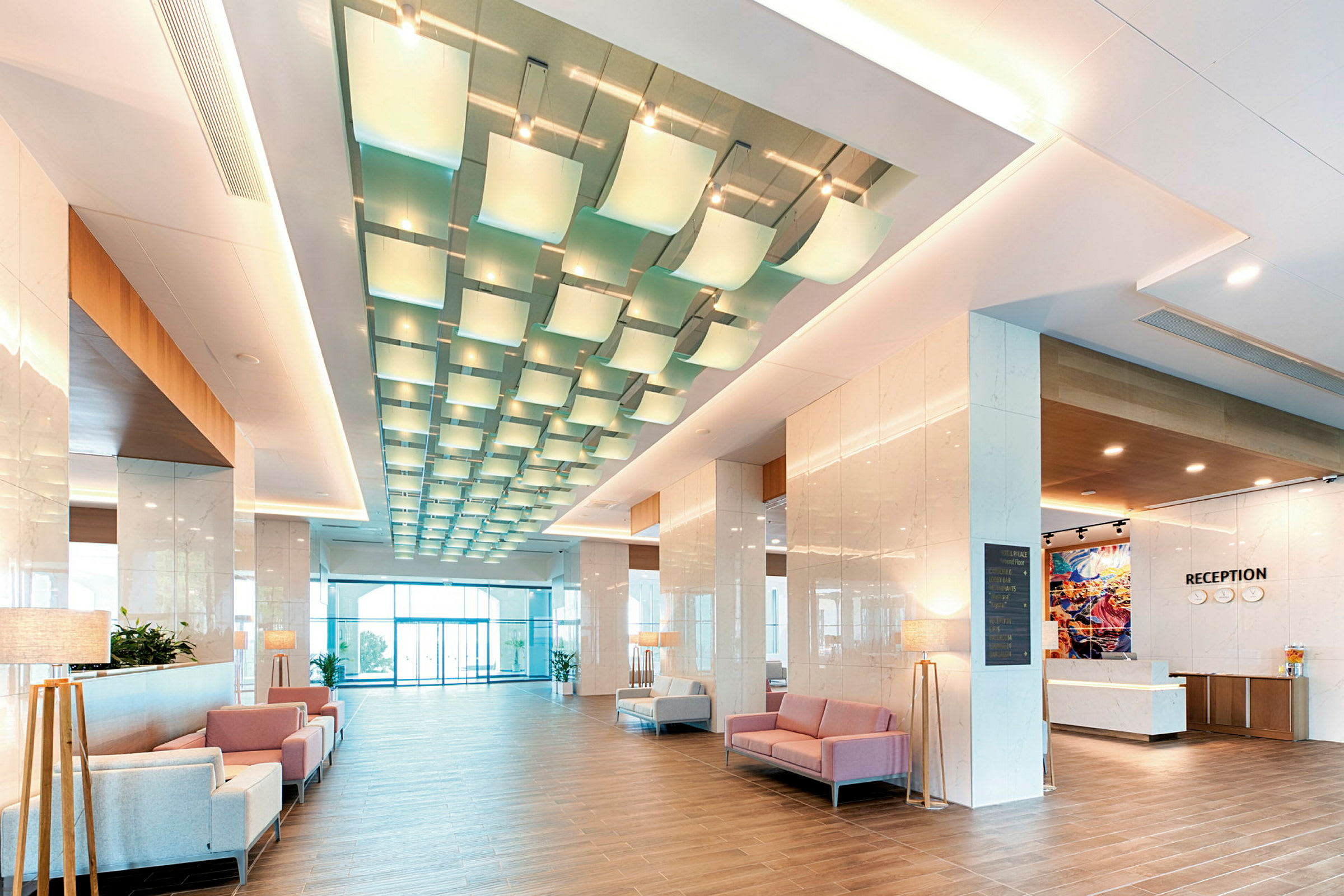 En bild av en modern hotelllobby med sittplatser, reception, och dekorativ belysning. (AI-genererad text)