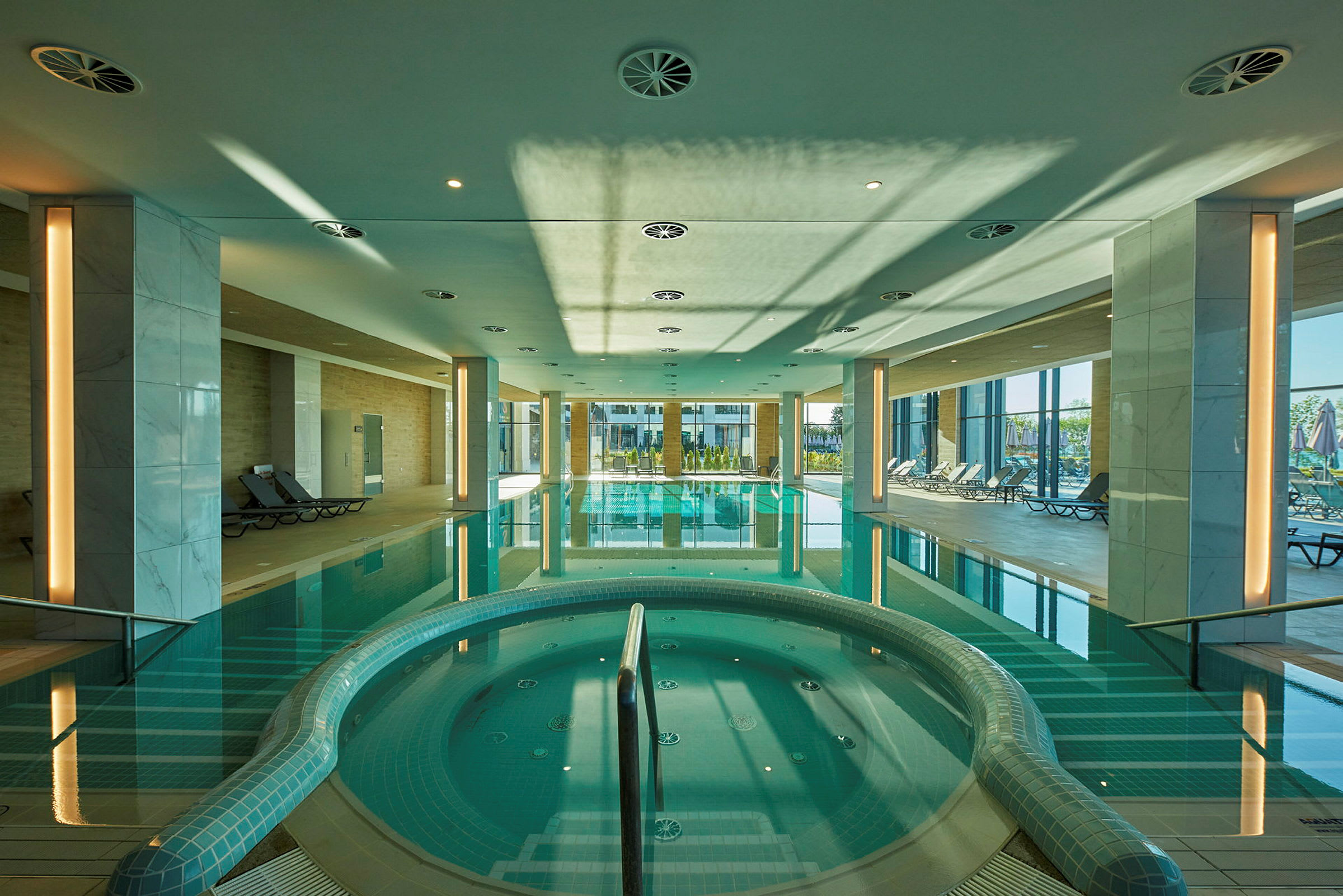Inomhuspoolområde med sittplatser och jacuzzi. (AI-genererad text)
