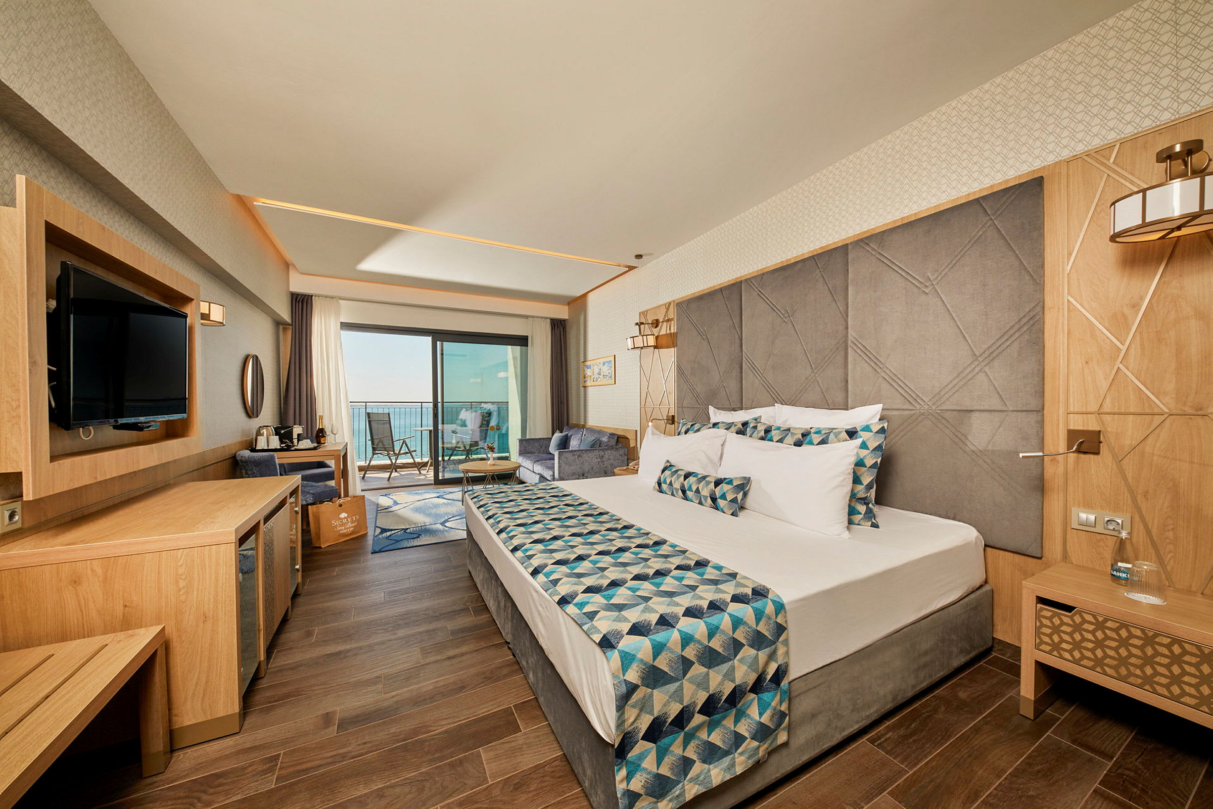 Hotellrum med modern inredning, dubbelsäng och balkong med havsutsikt. (AI-genererad text)