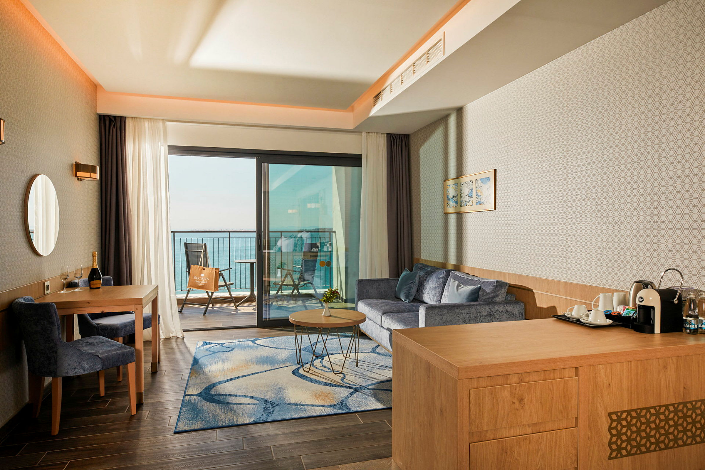 Hotellrum med sittgrupp och utsikt över havet från balkongen. (AI-genererad text)