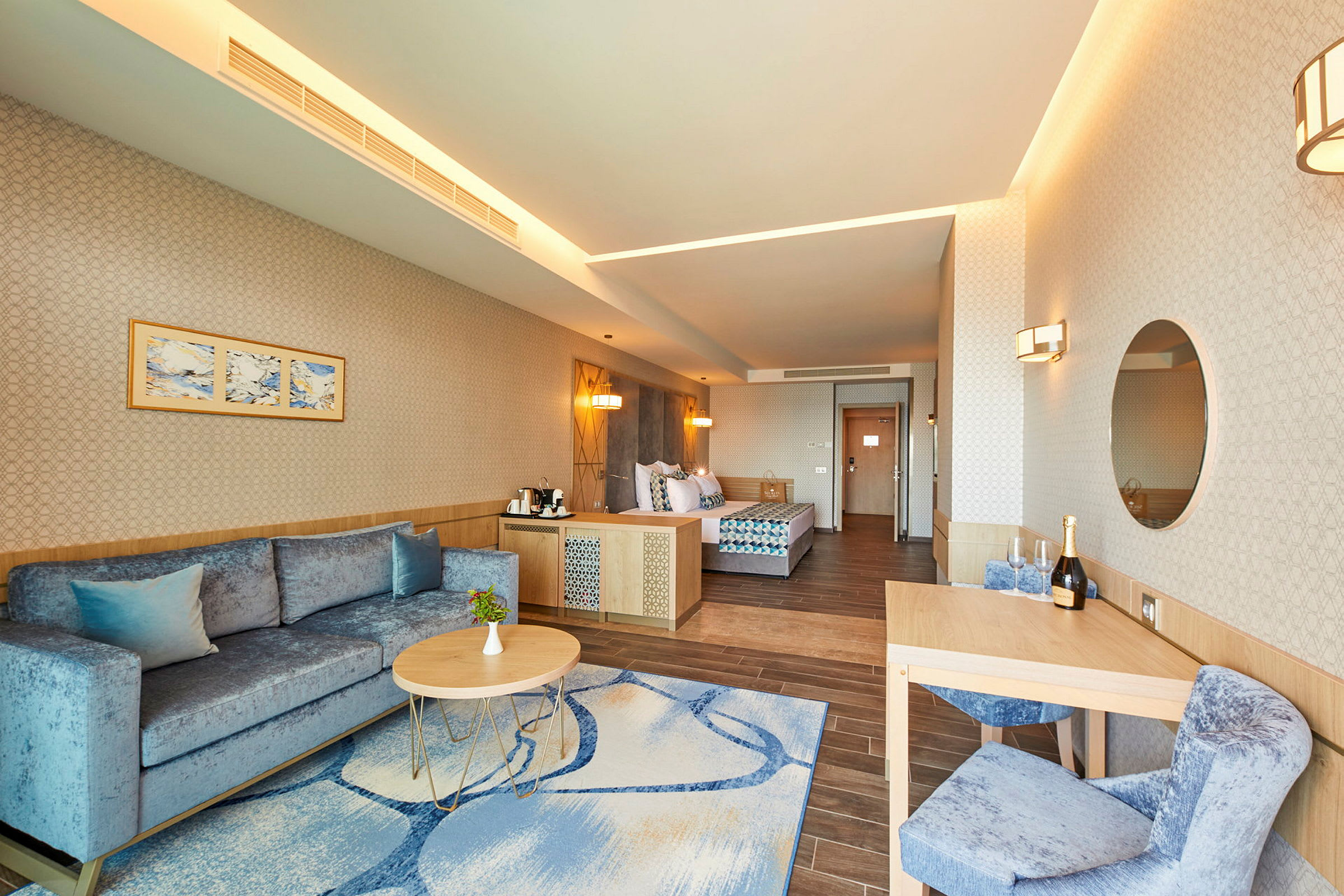 Interiör av ett hotellrum med en soffa, soffbord, matbord och en säng. (AI-genererad text)