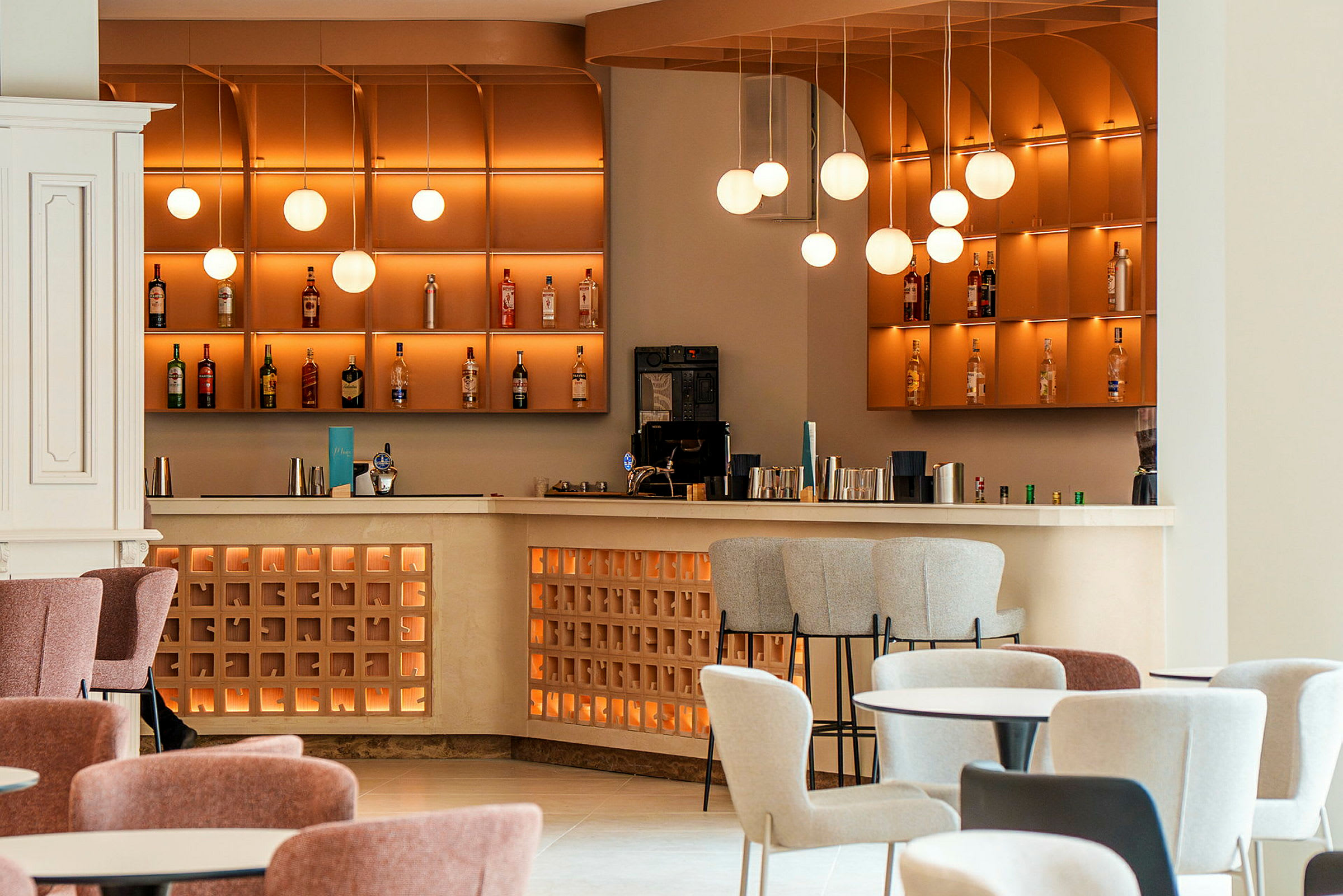 En modern bar med stolar framför en välbelyst hylla fylld med flaskor. (AI-genererad text)