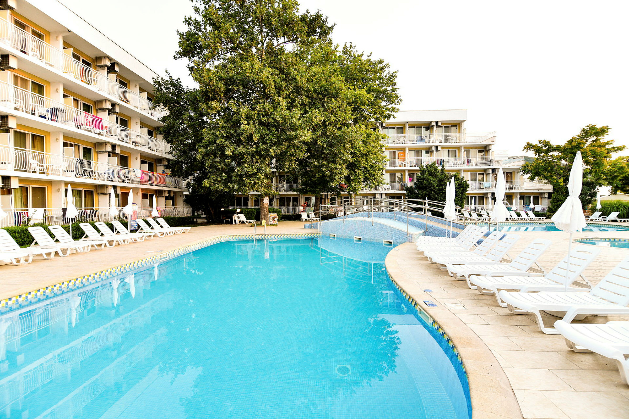 Bild av en utomhuspool vid ett hotell med solstolar och grönska. (AI-genererad text)