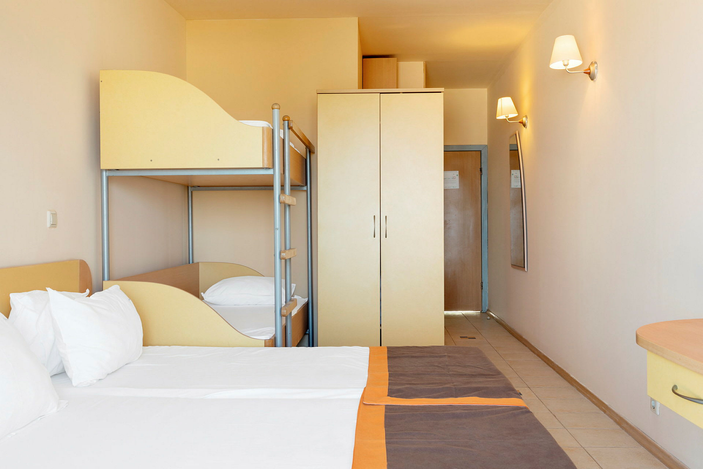 Hotellrum med dubbelsäng, våningssäng och garderob. (AI-genererad text)