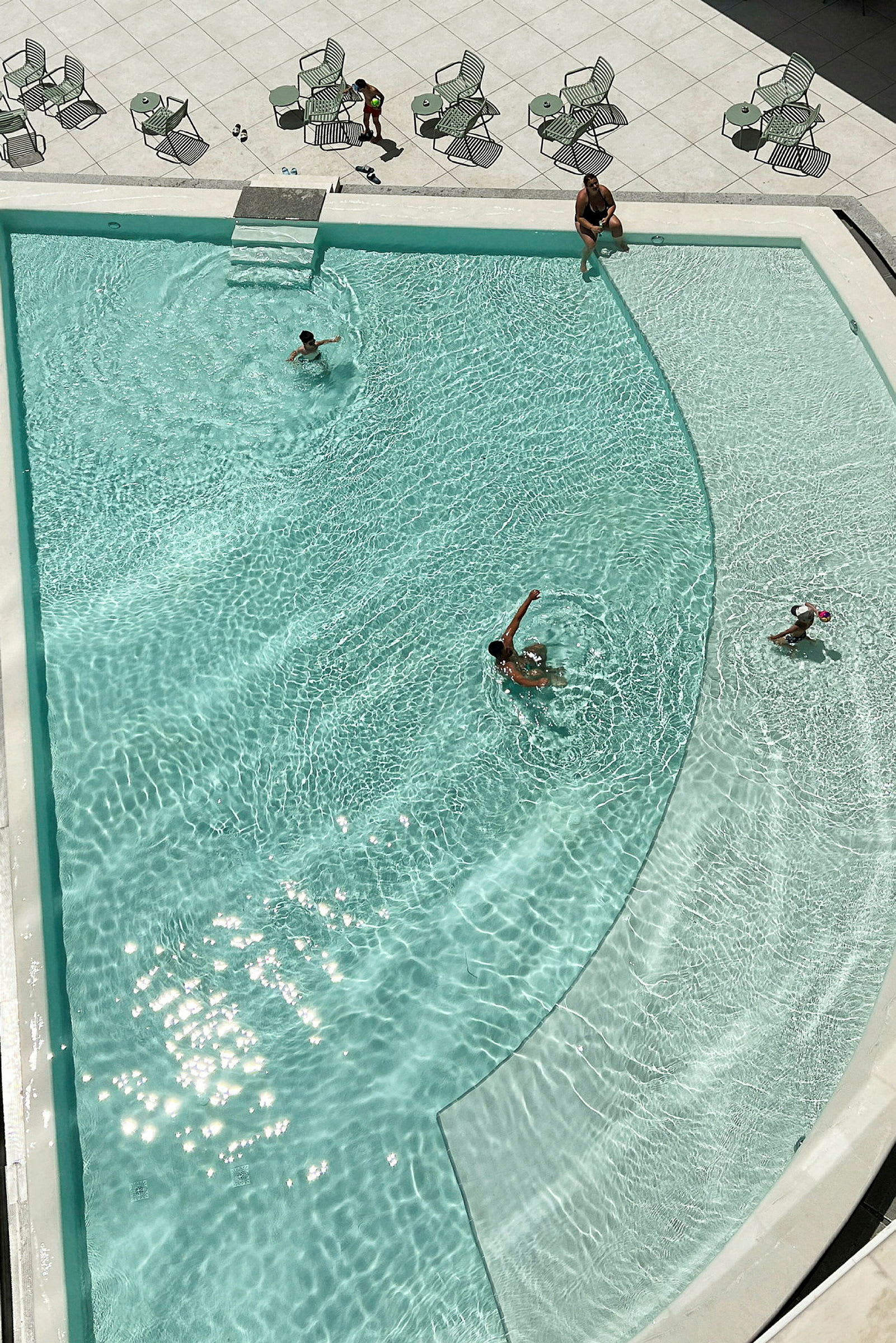 Överblick av en pool med personer som simmar och kopplar av. (AI-genererad text)