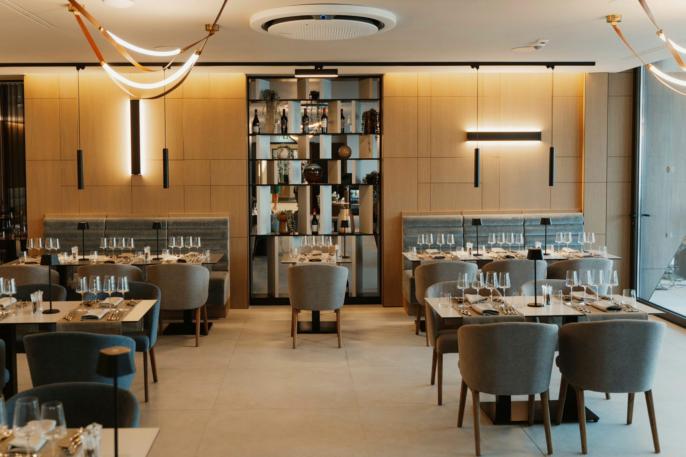 Restaurang med dukade bord och bekväma stolar, samt dekorativa lampor i taket. (AI-genererad text)