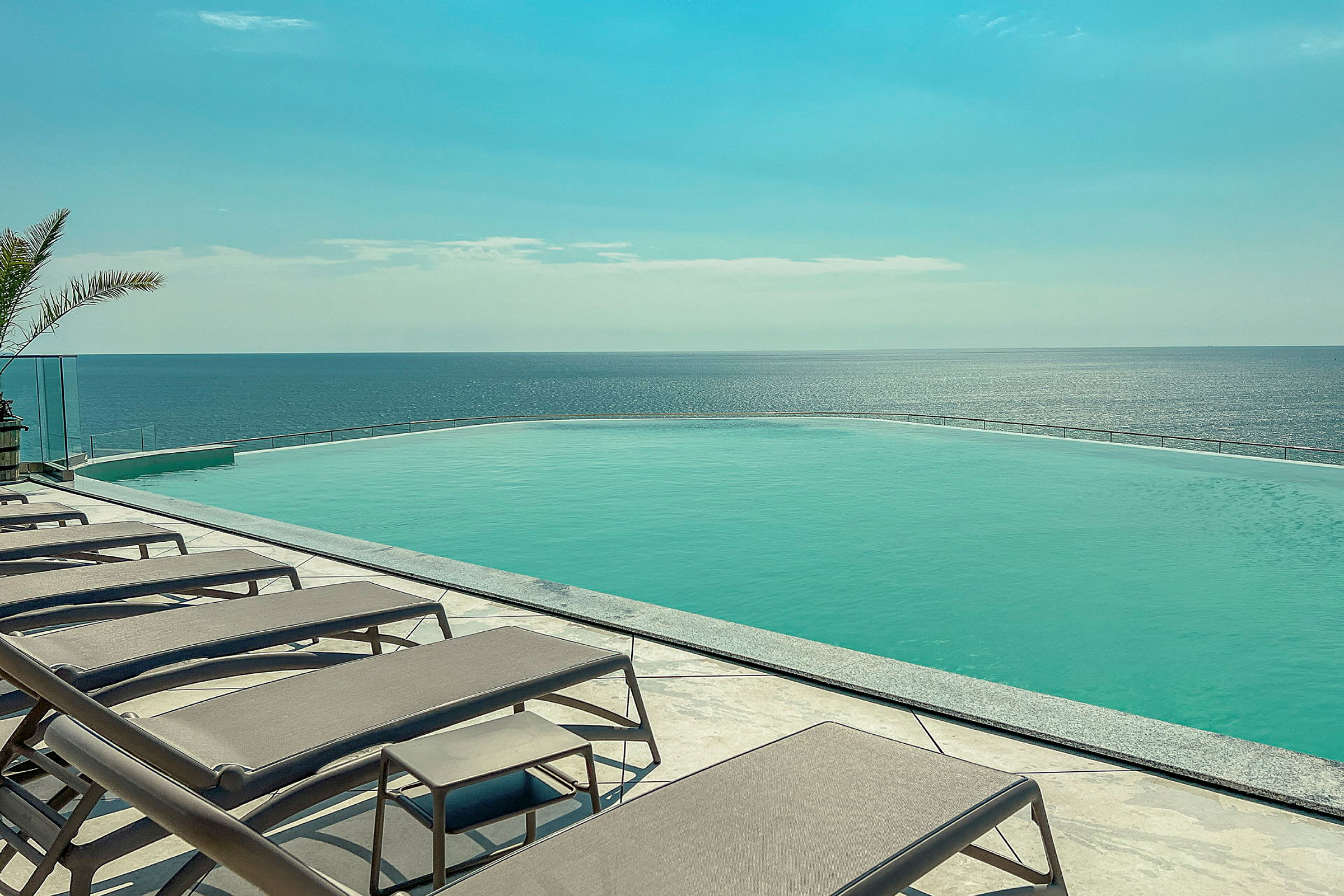 Solstolar vid en infinitypool som vetter mot havet. (AI-genererad text)