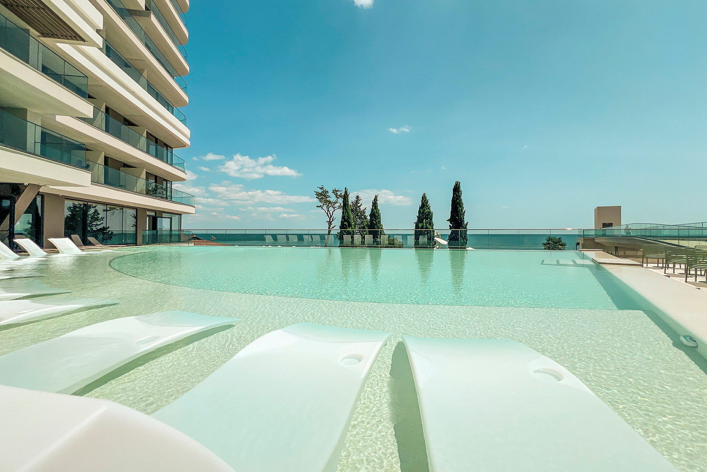 Modern byggnad med pool och utsikt över havet. (AI-genererad text)
