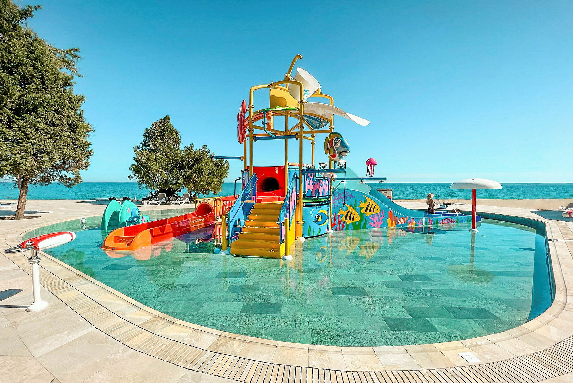 Bild av en vattenpark med färgglada lekstrukturer och rutschkanor vid en pool. (AI-genererad text)