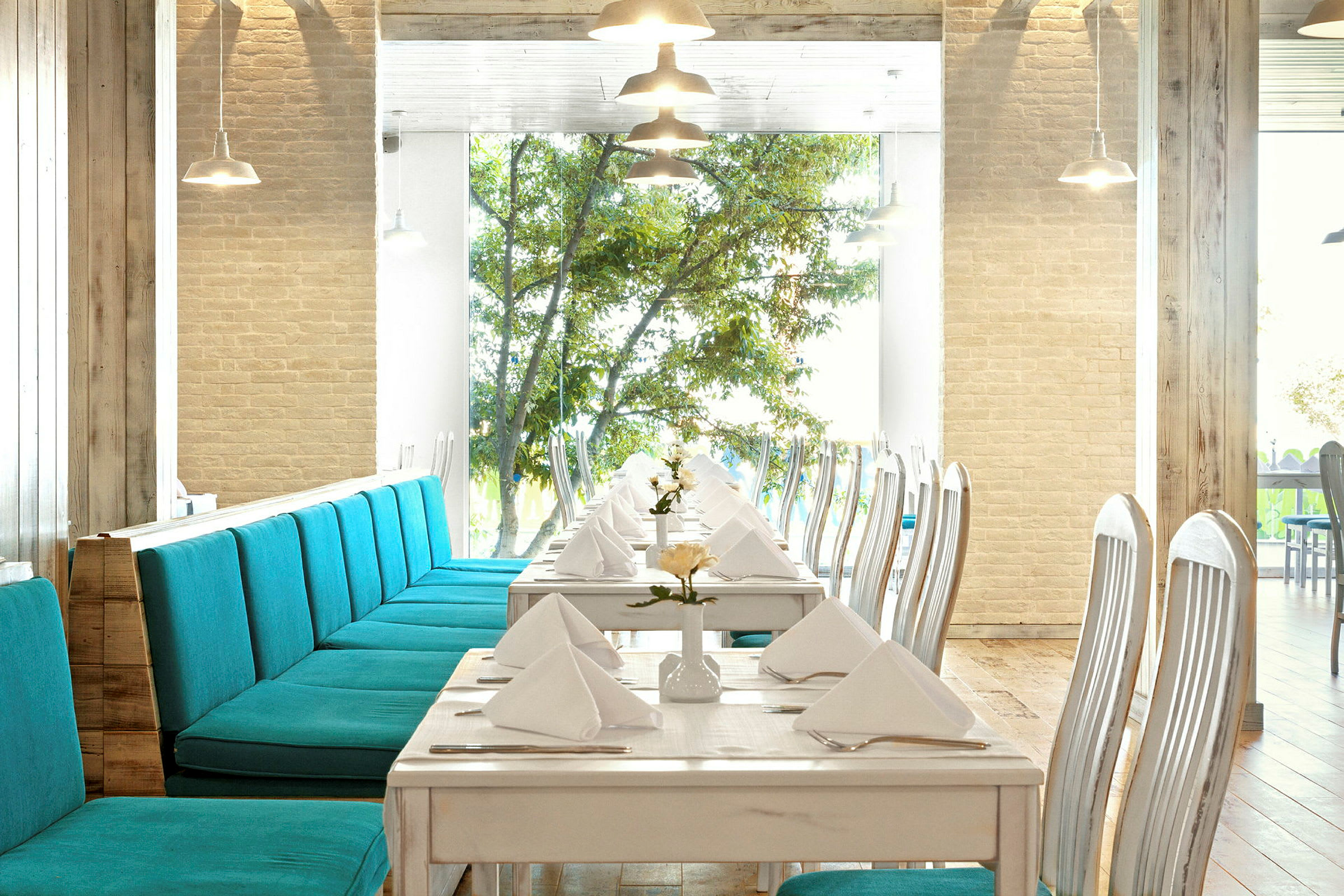 Restaurang med dukade bord och turkosa soffor. (AI-genererad text)