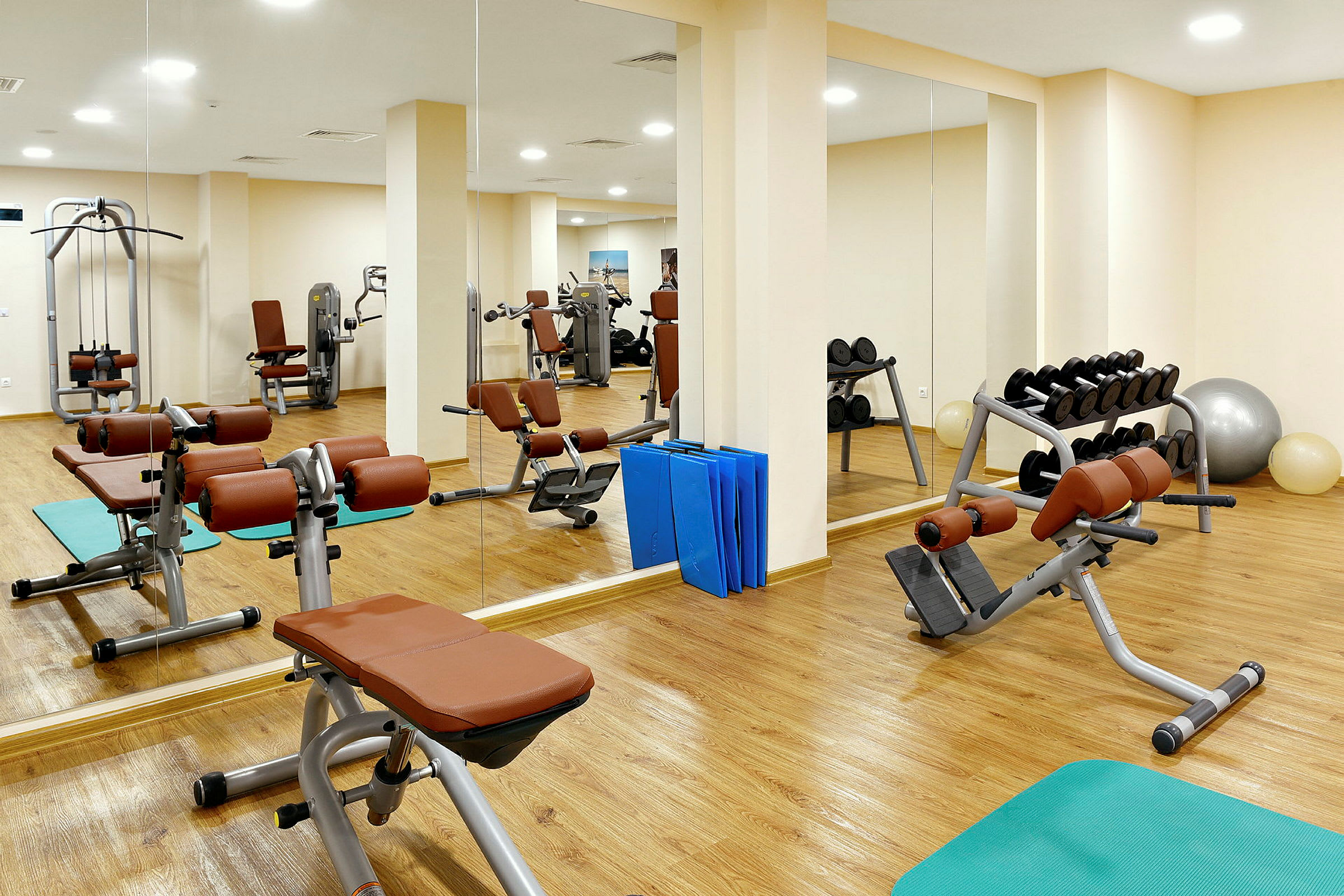 Ett gym med träningsmaskiner, vikter och speglar. (AI-genererad text)
