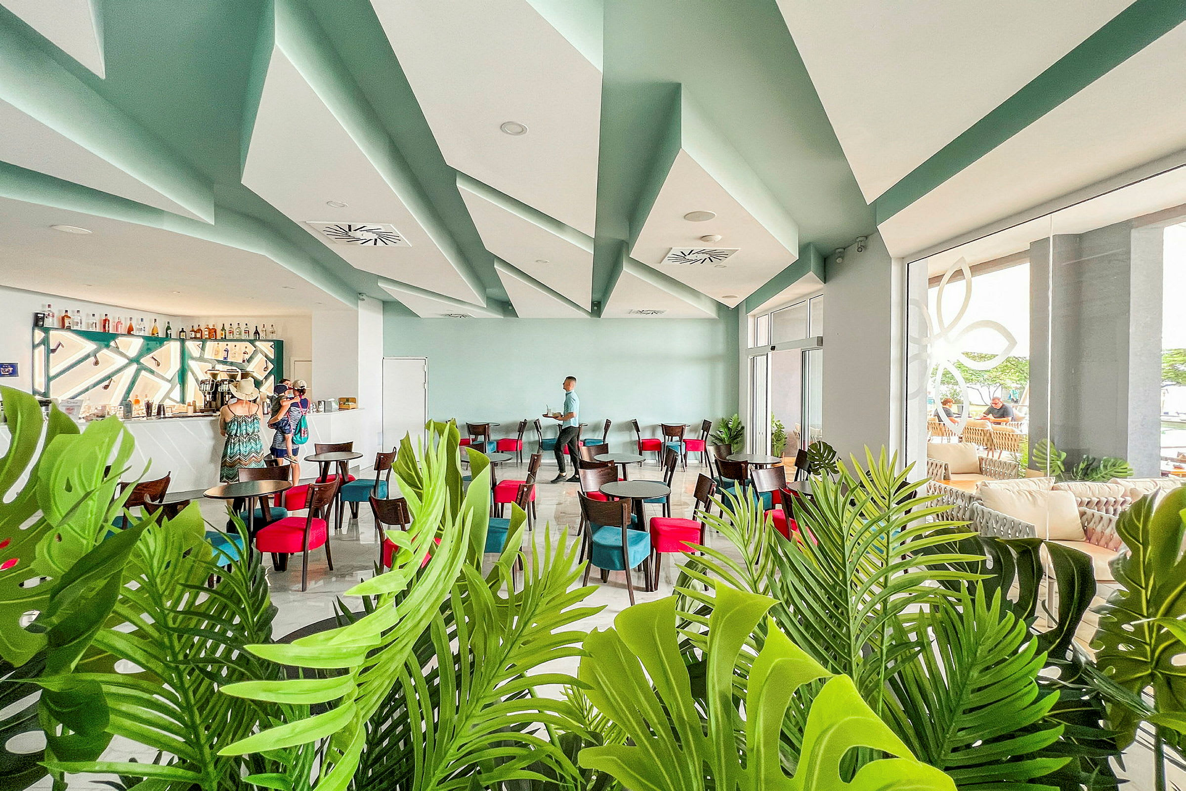 Modern caféinteriör med sittgrupper och barområde, dekorerad med gröna växter. (AI-genererad text)