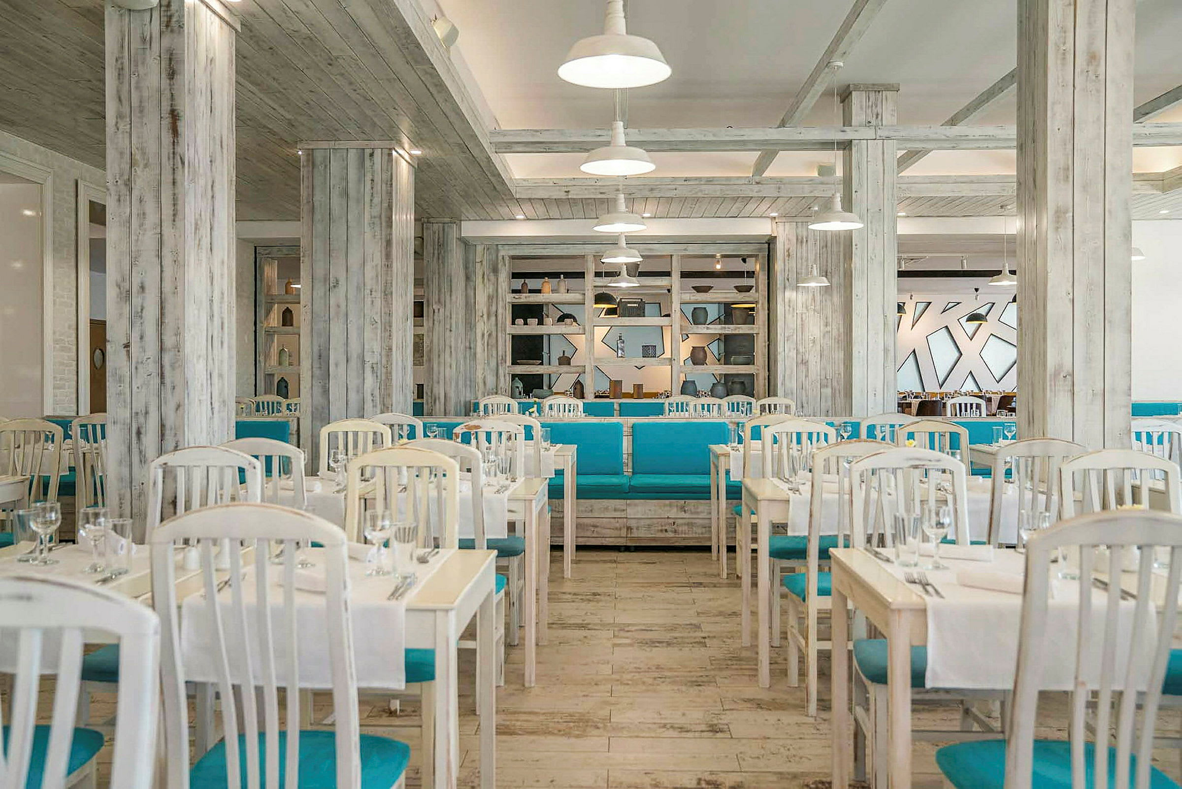 Ett ljusrestaurang med vita bord, blå stolar och en stilren inredning. (AI-genererad text)