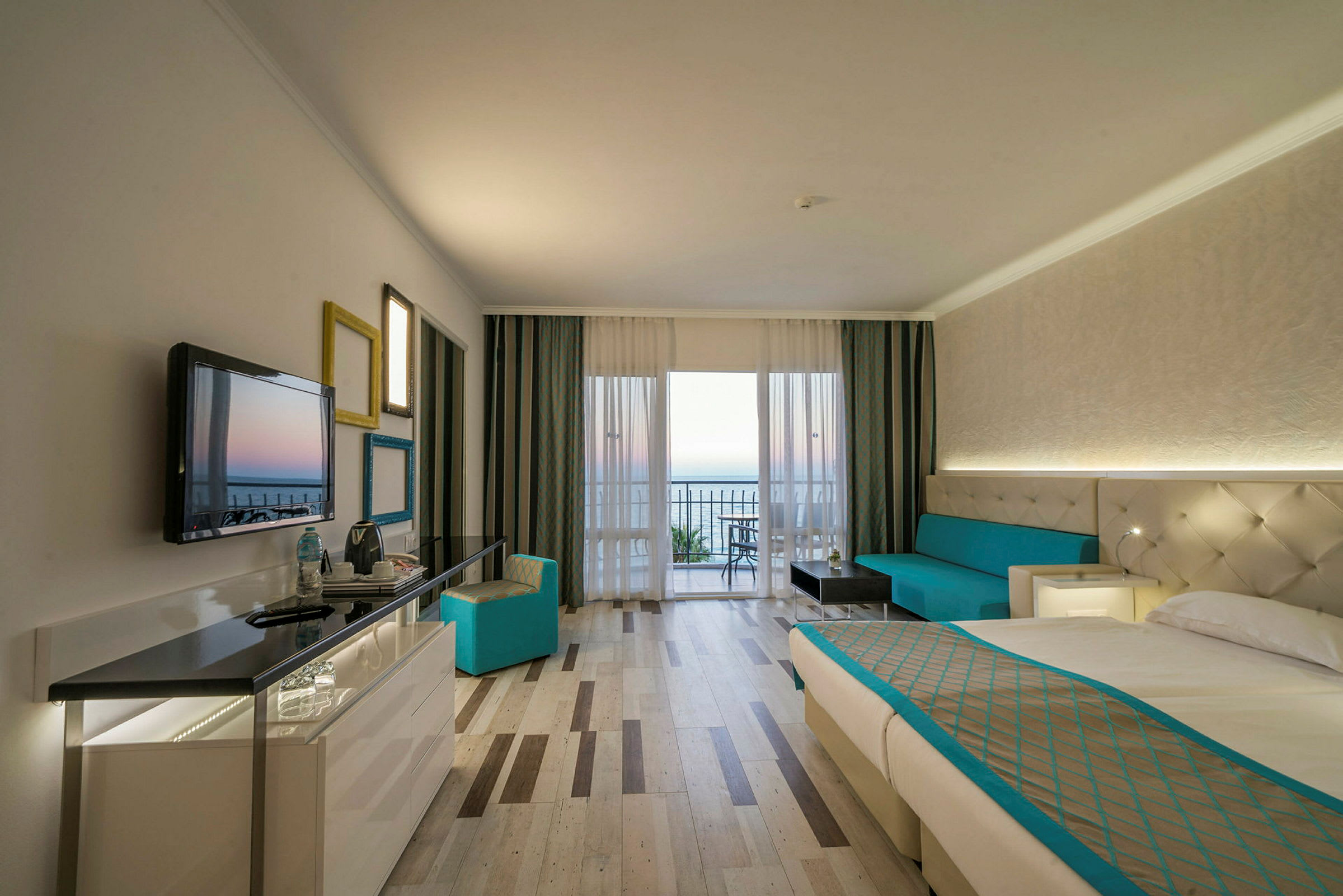 Interiör av ett hotellrum med en säng, soffa och utsikt mot en balkong. (AI-genererad text)