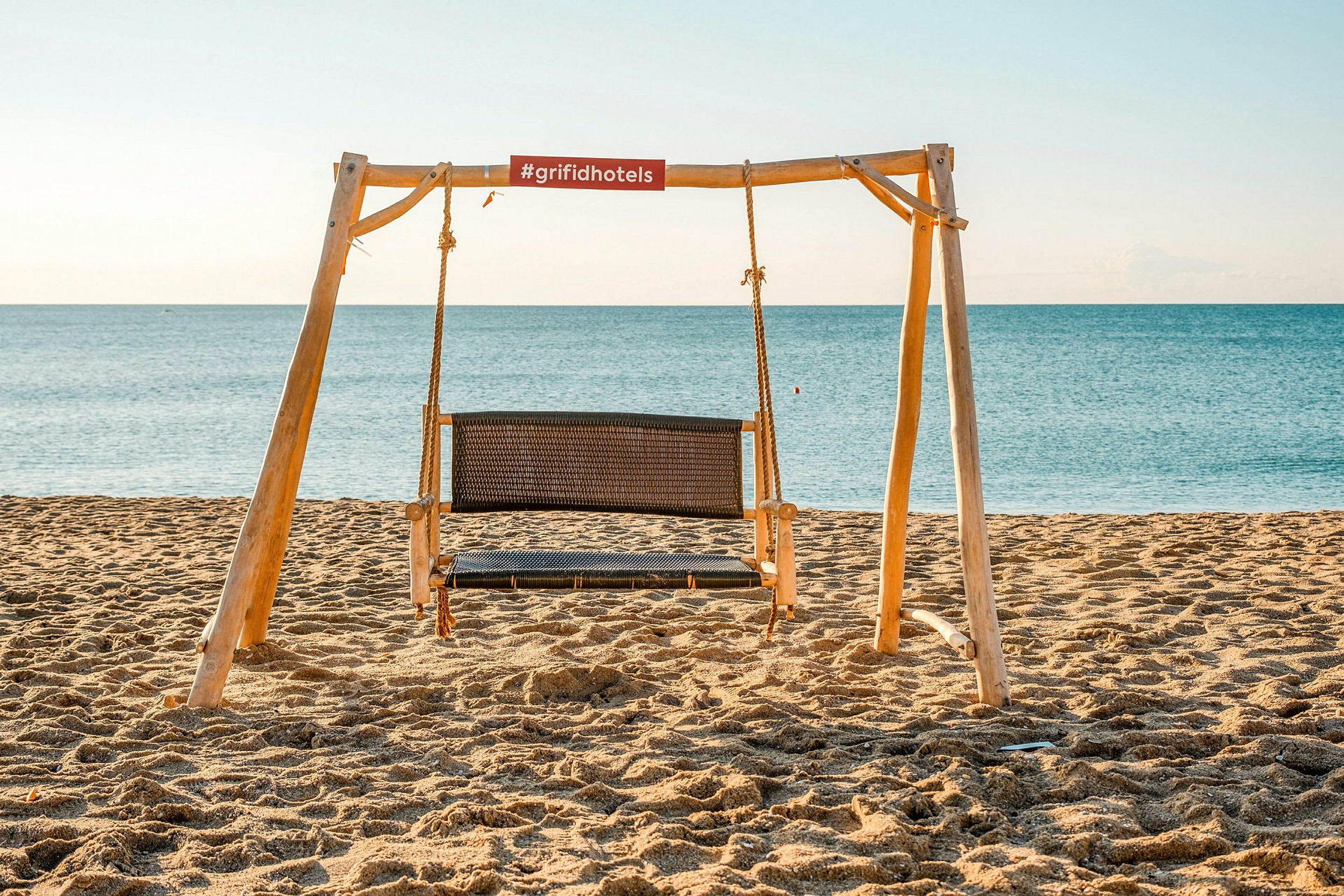 En trägungställning med en sittgunga på en sandstrand vid havet. (AI-genererad text)