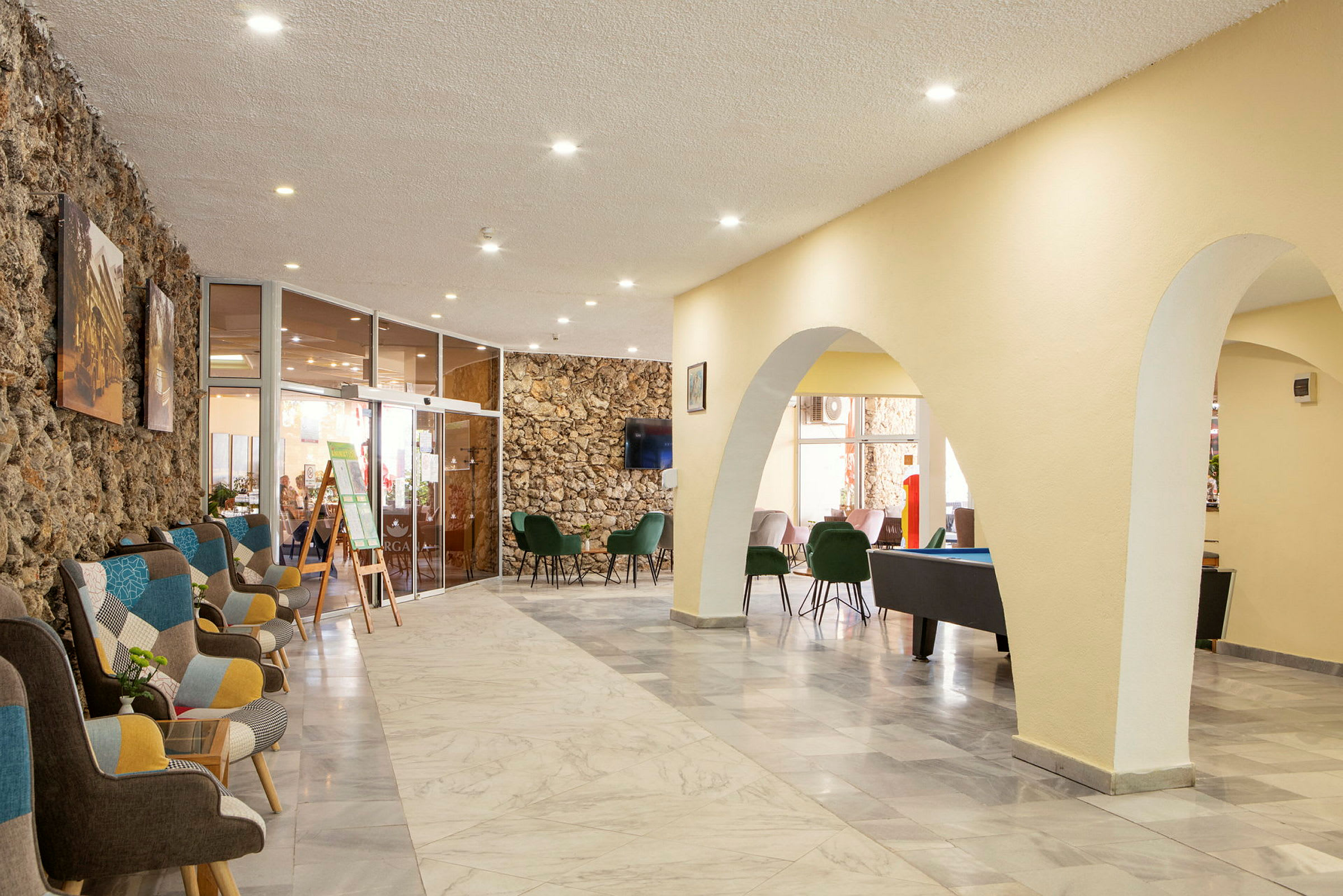 Interiör av en ljus och rymlig lobby med bekväma sittplatser och stenväggar. (AI-genererad text)