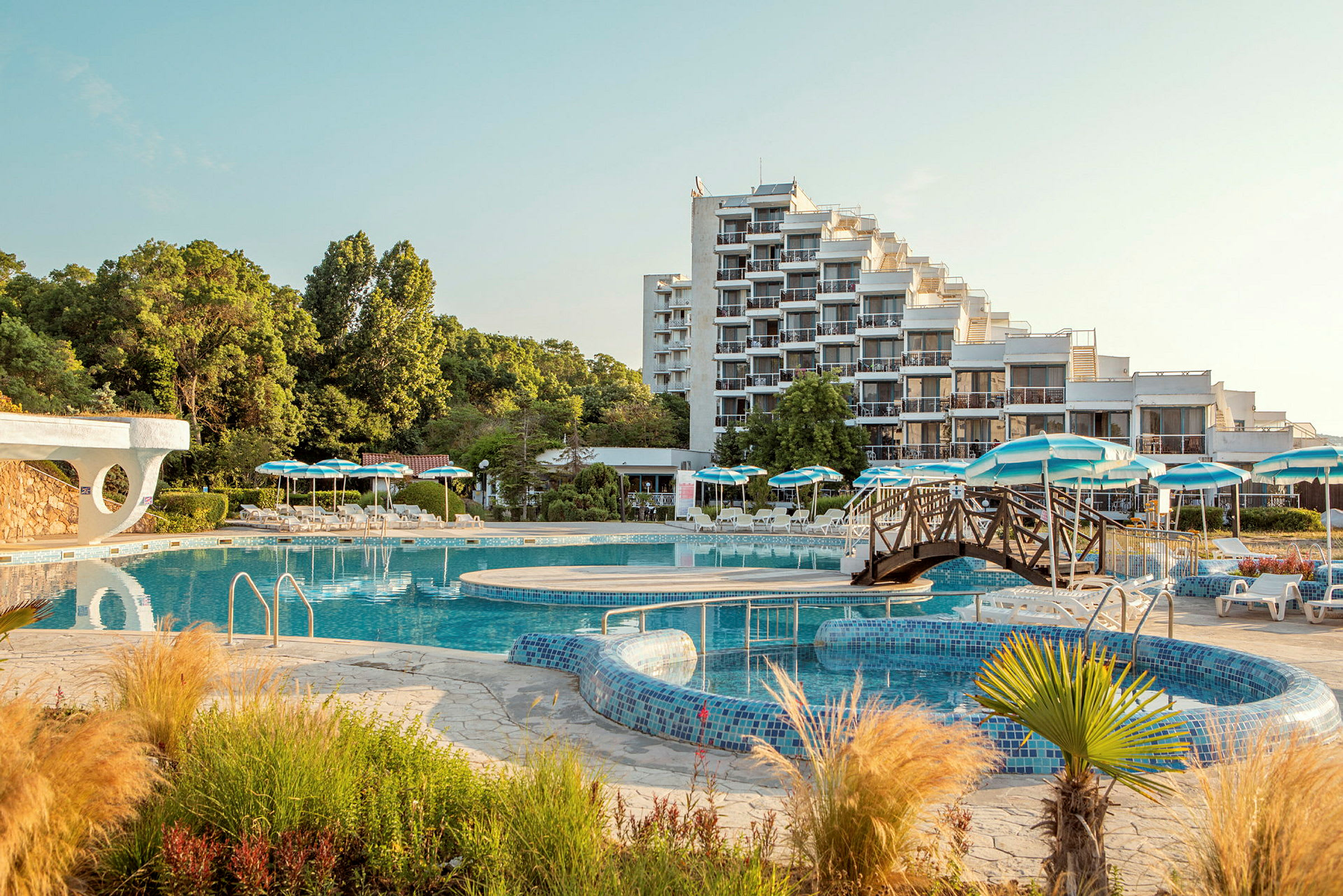 Hotell med en stor poolområde och parasoller bland grönska. (AI-genererad text)