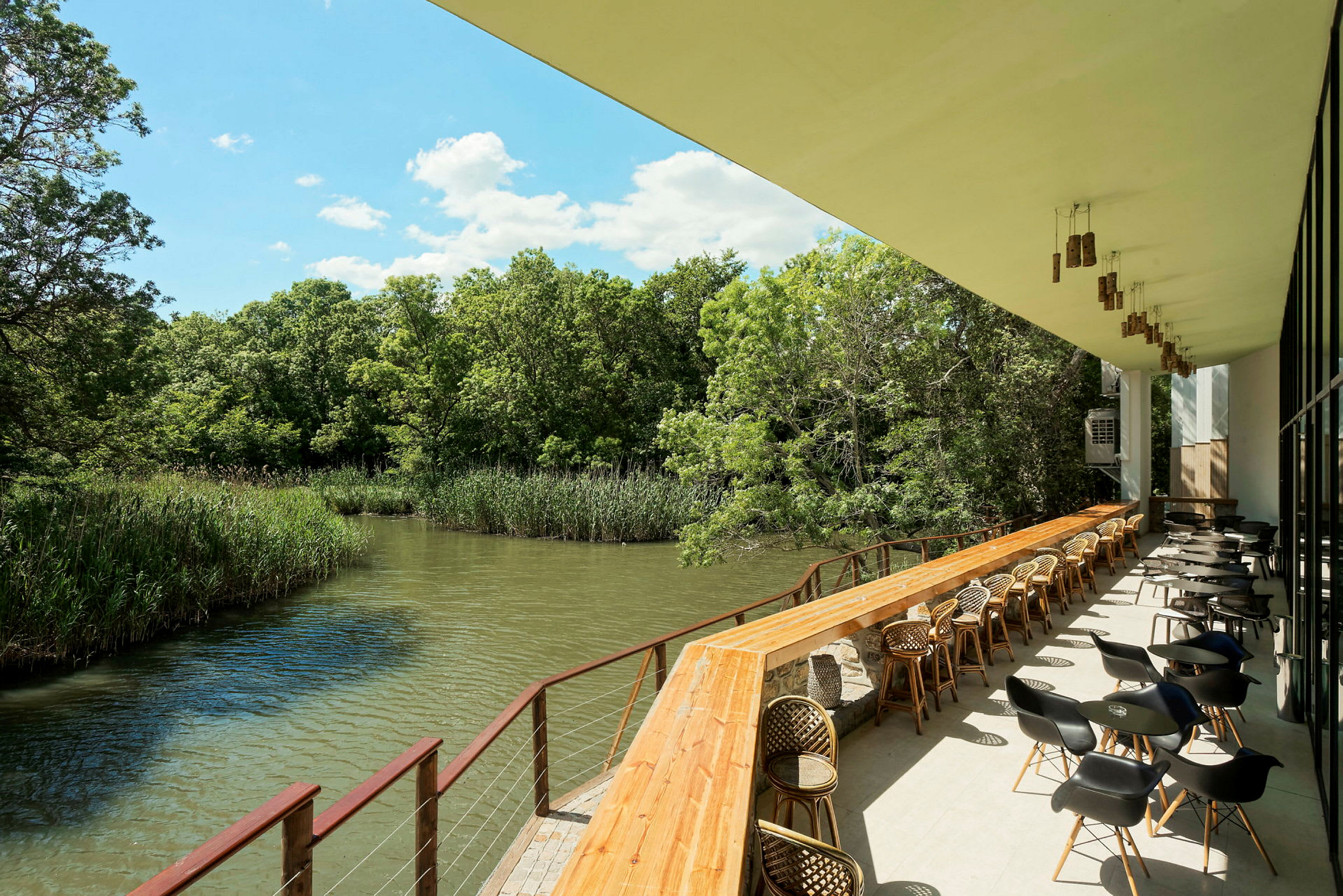 En restaurangveranda med utsikt över en flod omgiven av grönska. (AI-genererad text)