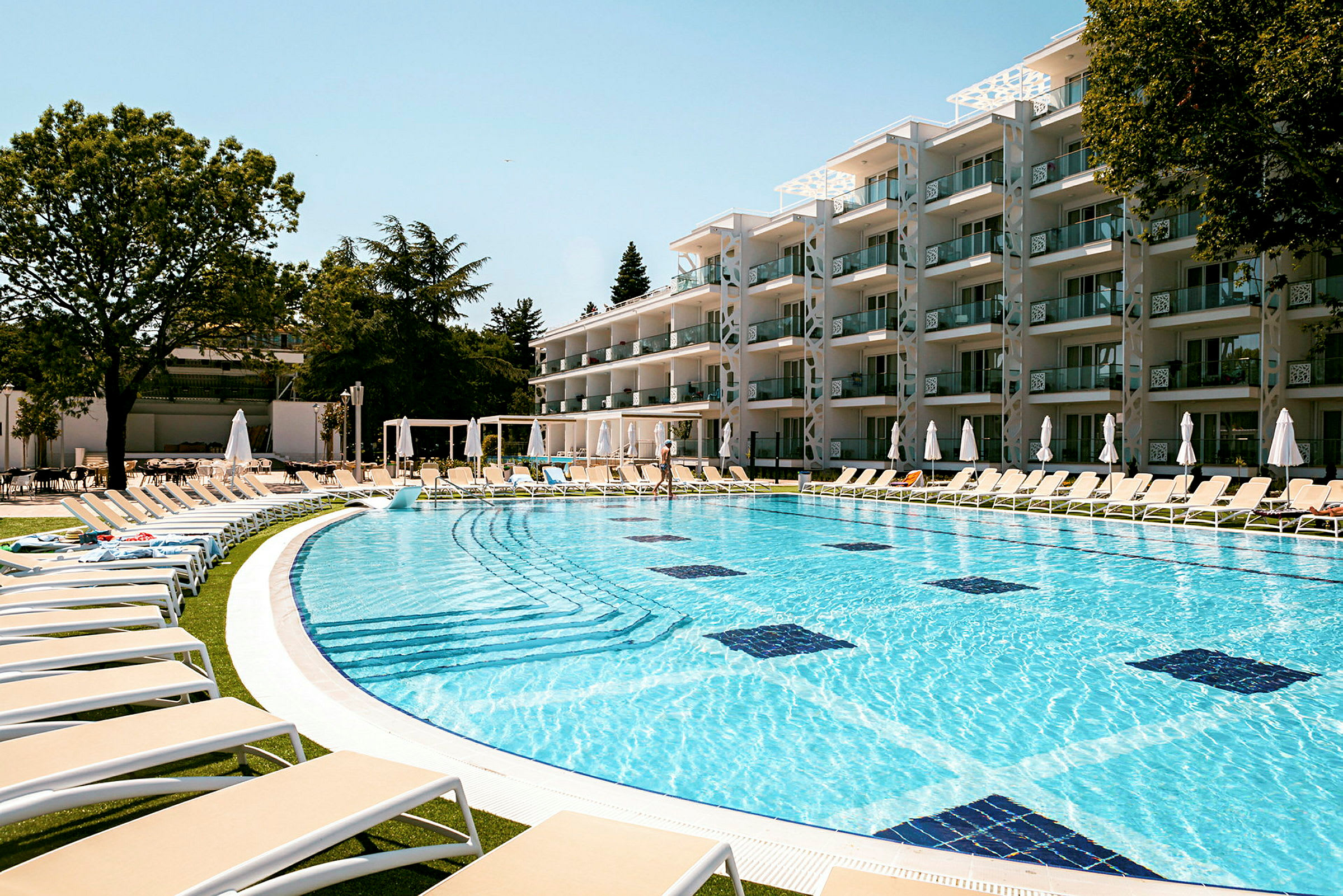 Bild av ett hotell med en utomhuspool omgiven av solstolar. (AI-genererad text)