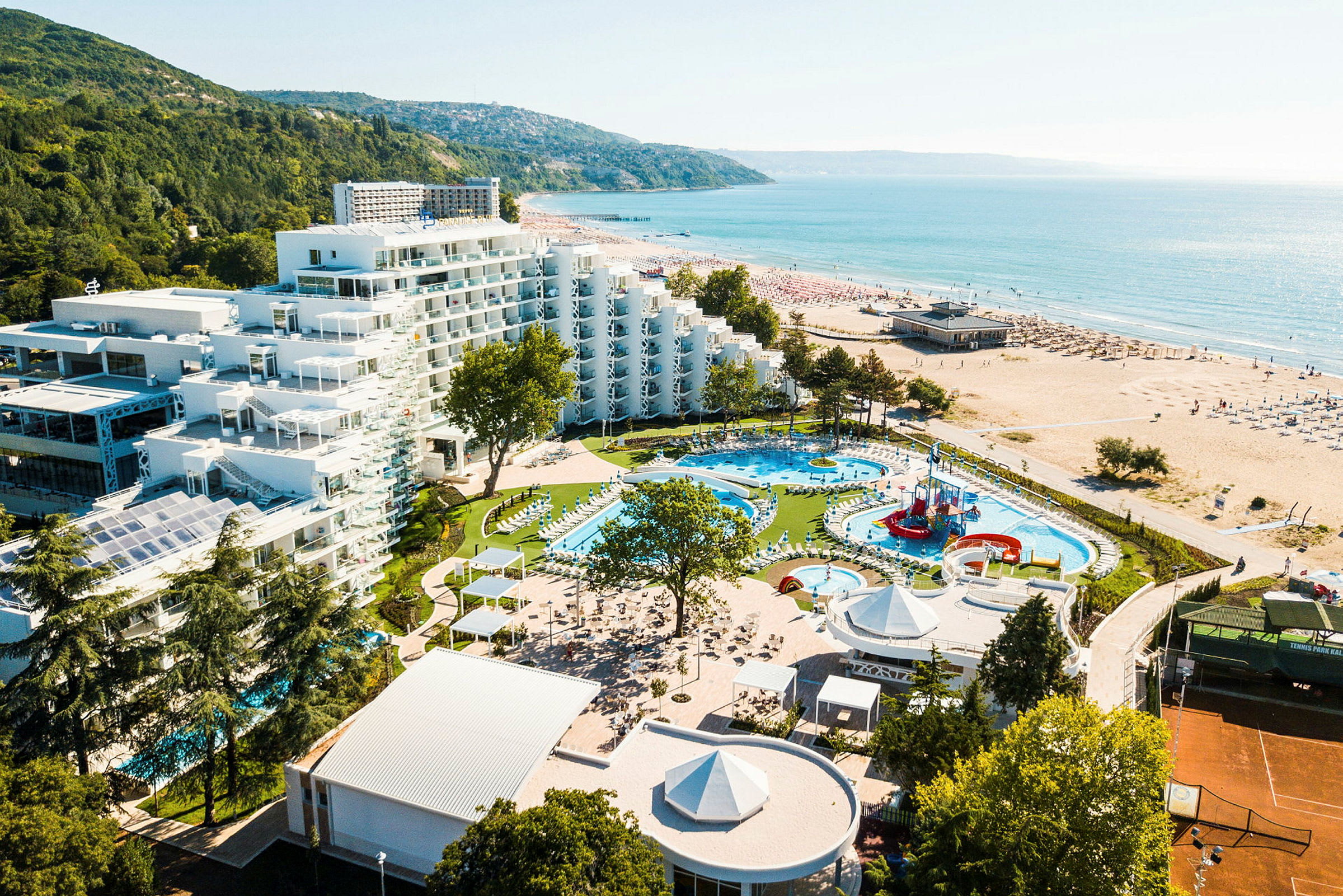 Bild av ett hotellkomplex med pooler och lekplats nära stranden. (AI-genererad text)