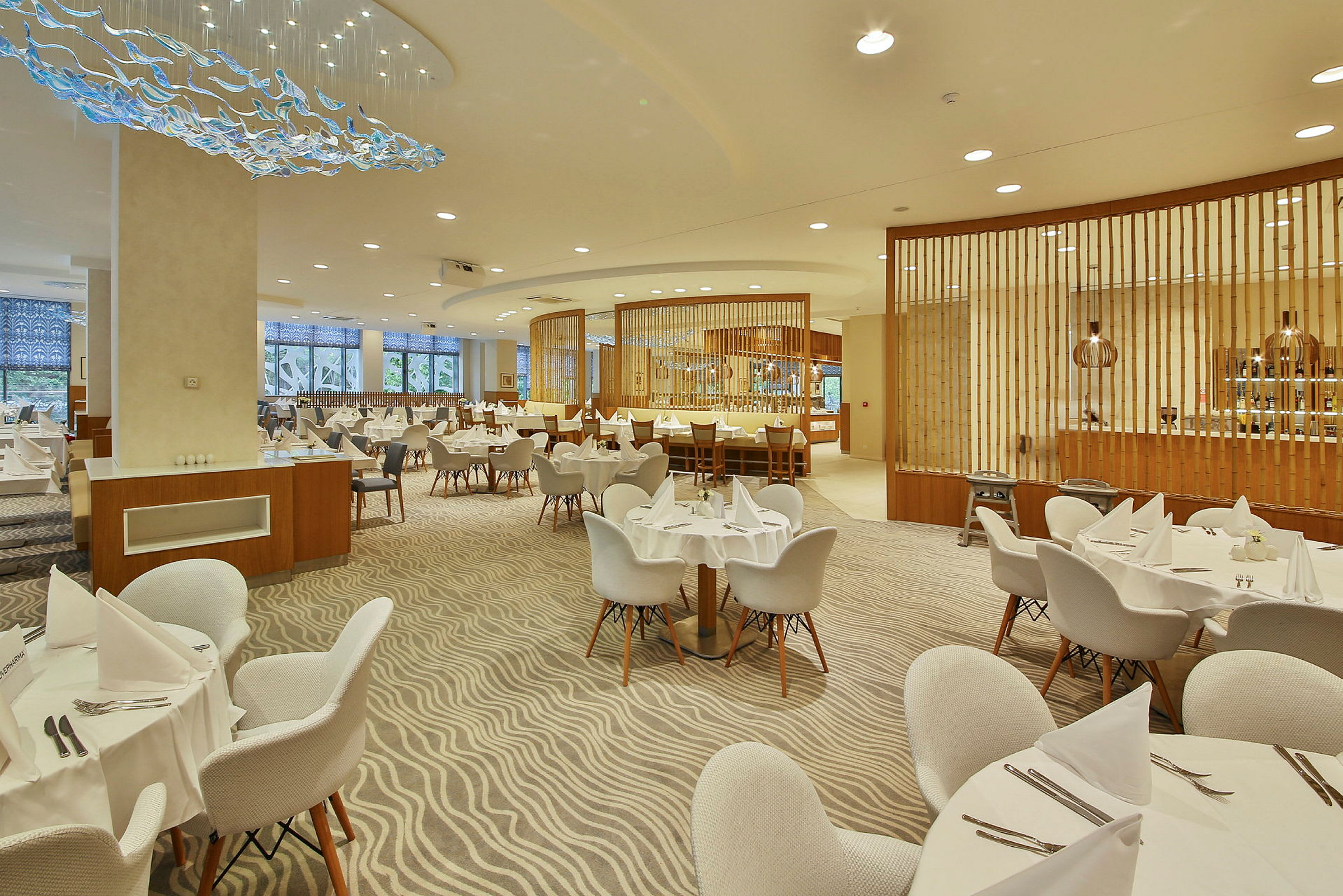En stor och välbelyst restaurang med dukade runda bord och moderna möbler. (AI-genererad text)