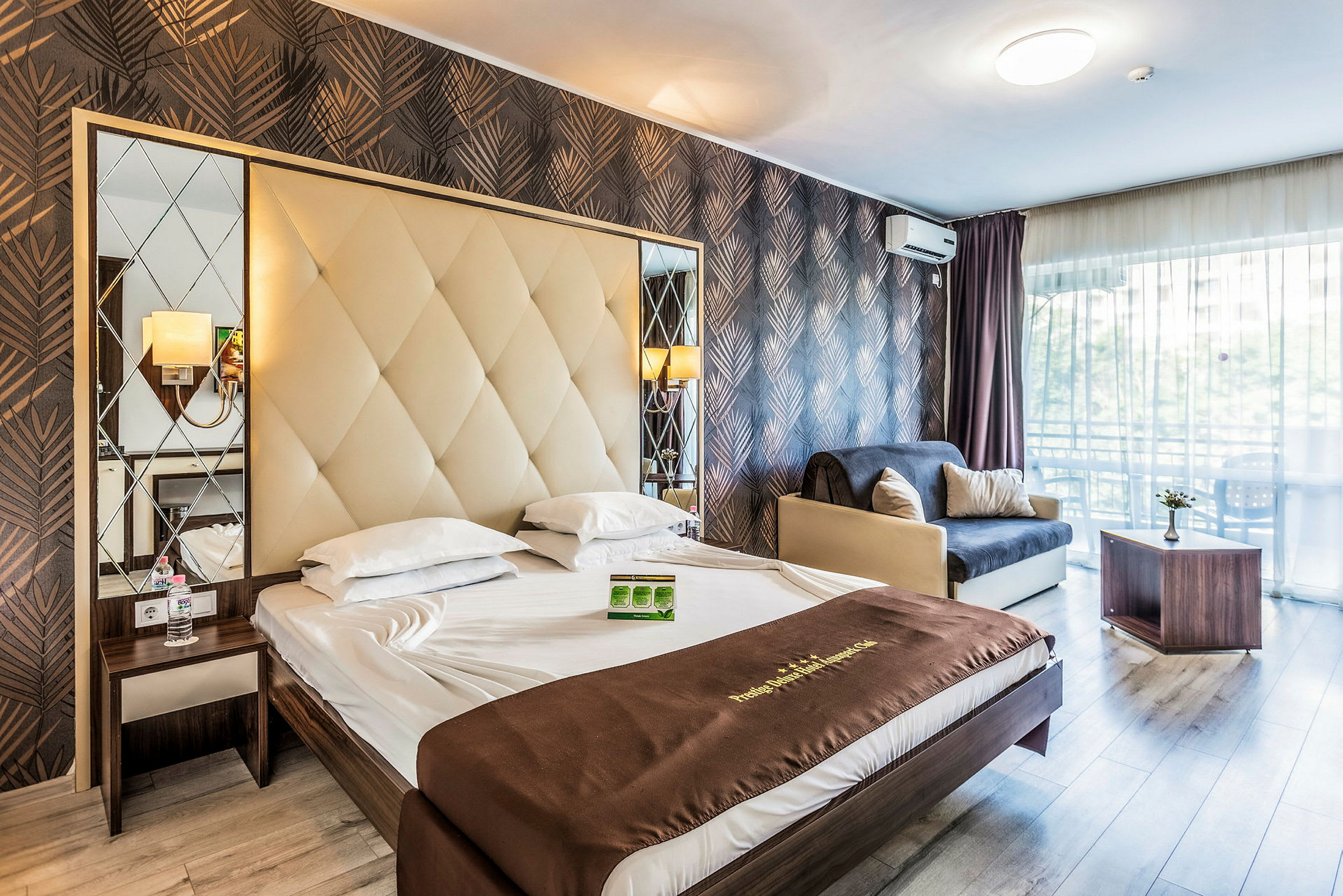 Ett hotellrum med en dubbelksäng, en soffa och ett bord. Rummet har en modern inredning med snygga mönstrade väggar. (AI-genererad text)