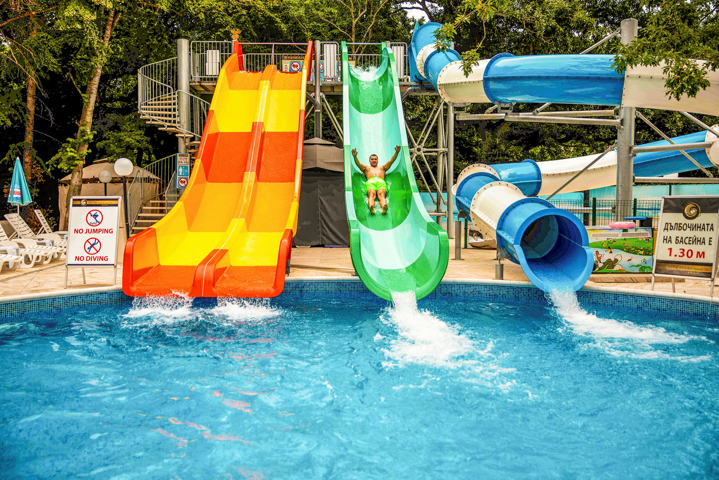 En vattenpark med tre rutschkanor som leder ner till en pool. (AI-genererad text)