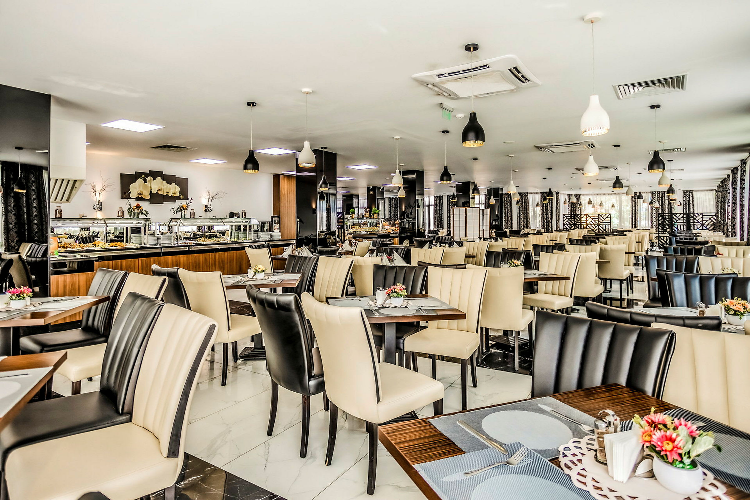 En restaurang med uppdukade bord och stolar i ljus och mörk färg, samt dekorationer och serveringsområden. (AI-genererad text)