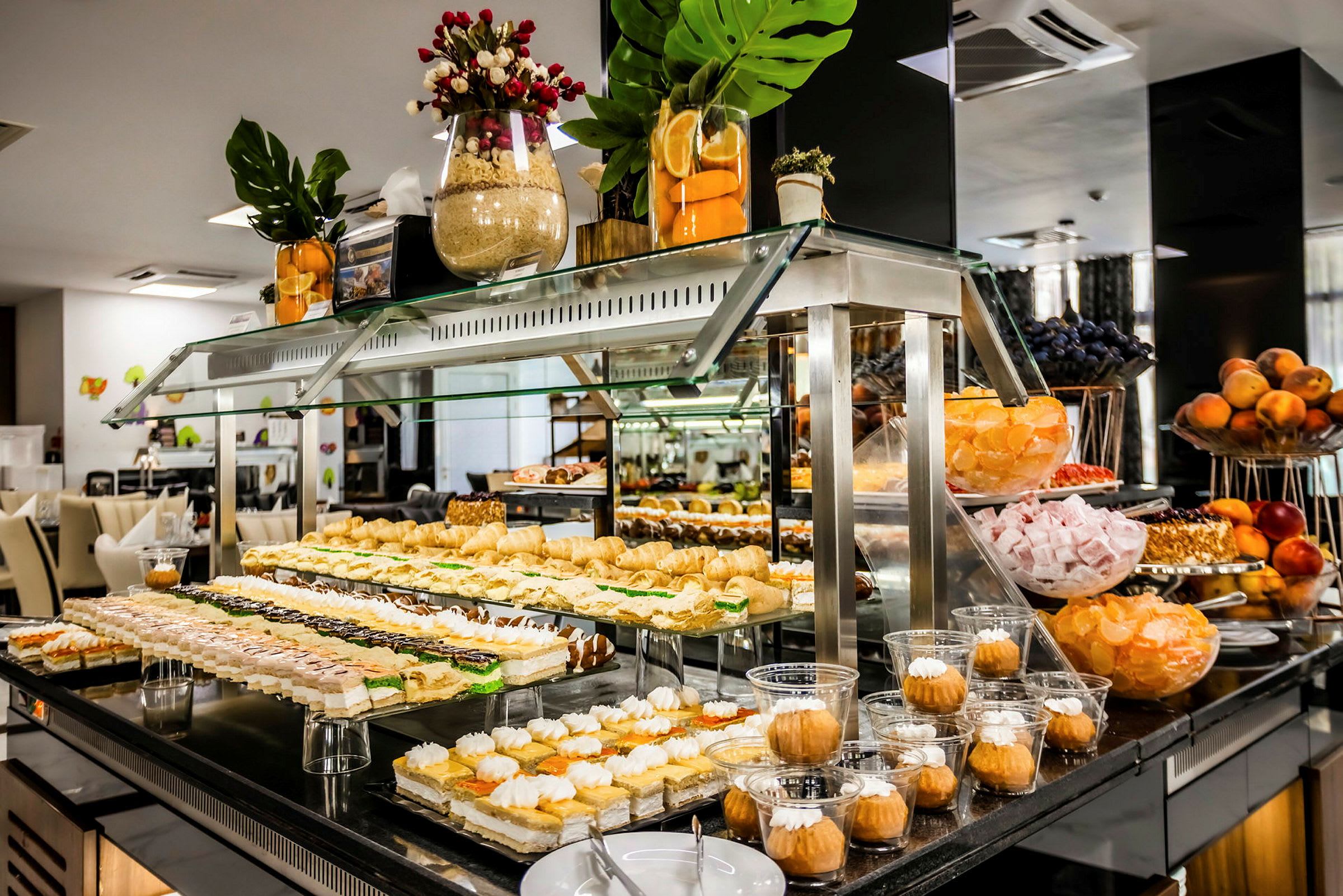 Bild av en buffé med olika desserter och sötsaker upplagda på glasmontrar. (AI-genererad text)