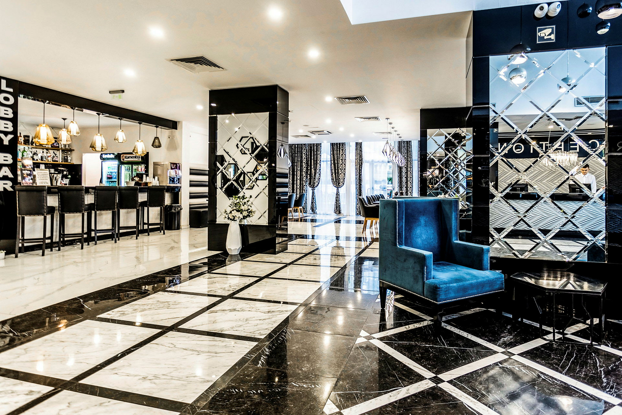 Hotellets lobby med marmorgolv, en reception i bakgrunden och en lobbybar på vänster sida. (AI-genererad text)