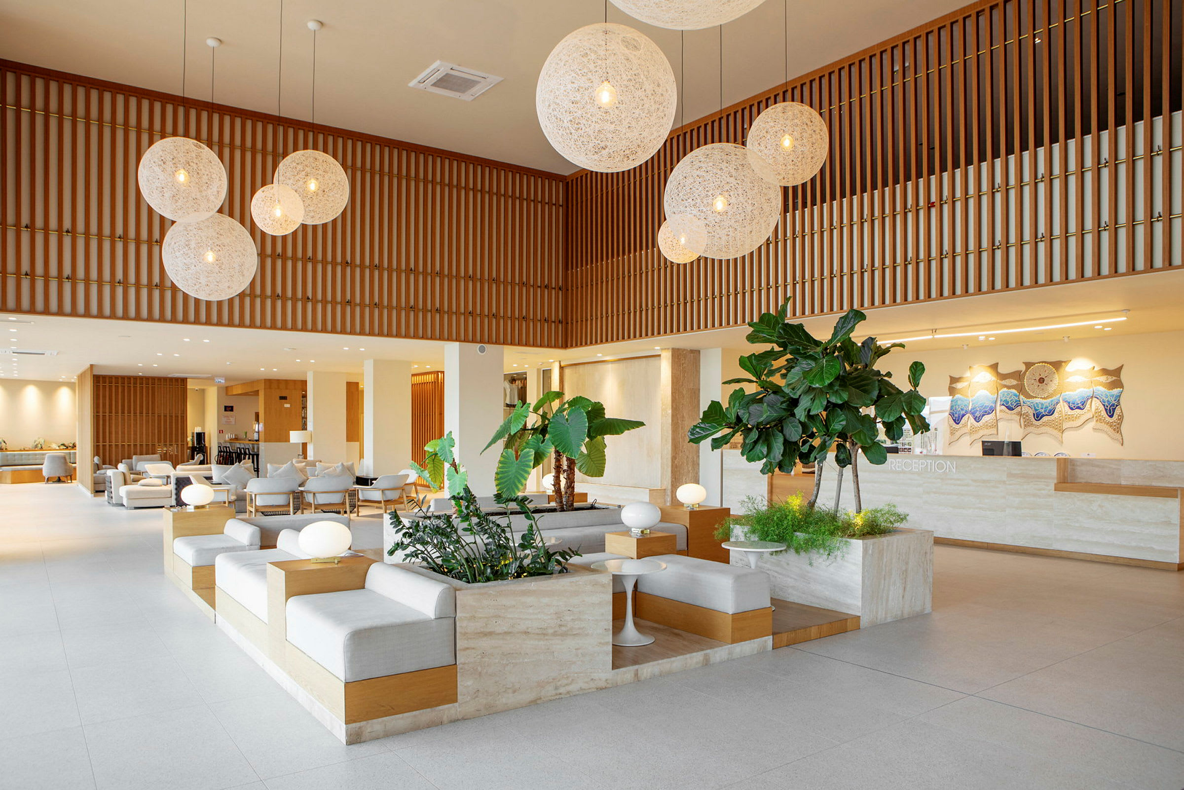 Ett modernt hotellobbyutrymme med sittplatser, växter och en reception. (AI-genererad text)