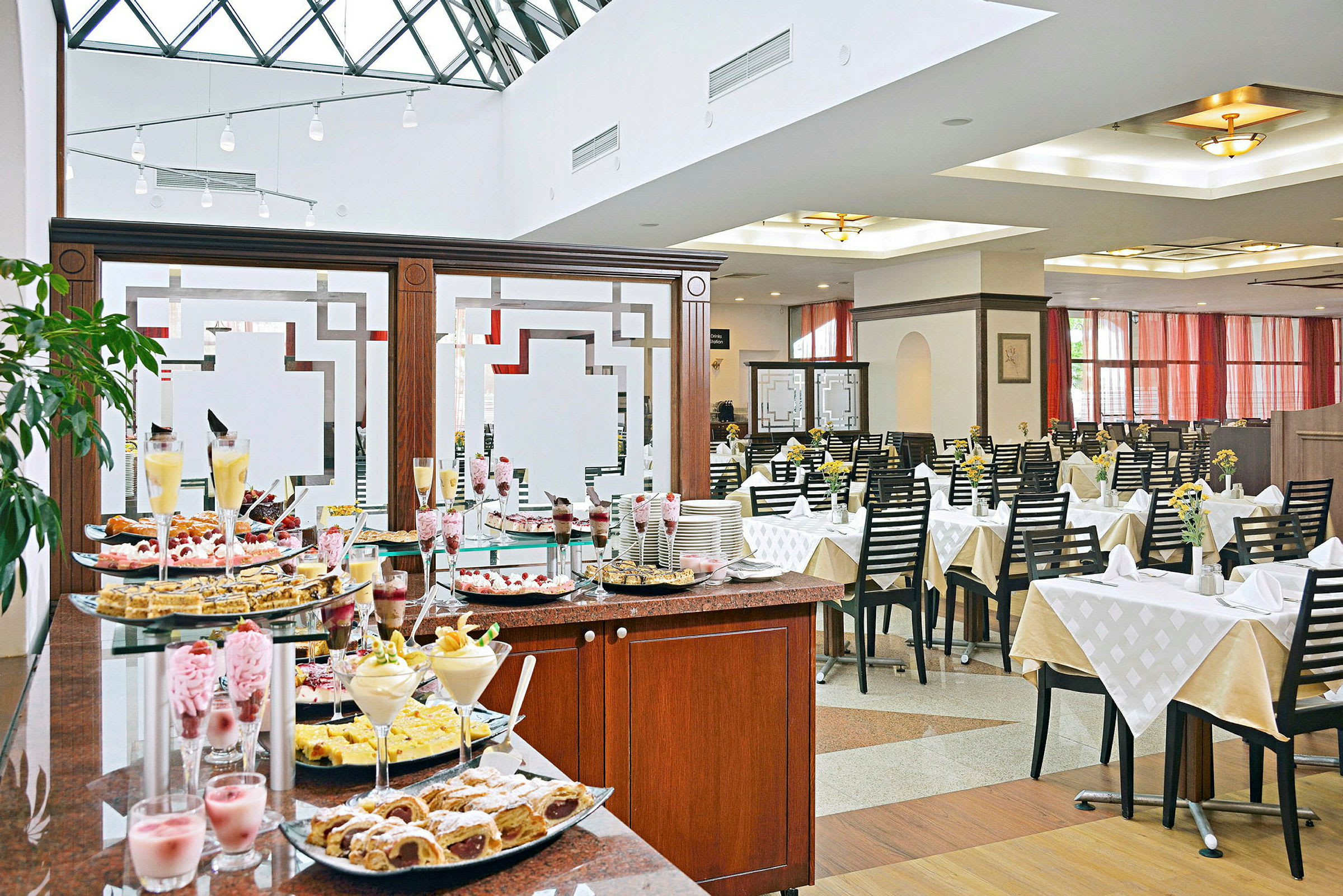 Buffébord med desserter i en ljus restaurang med dukade bord. (AI-genererad text)