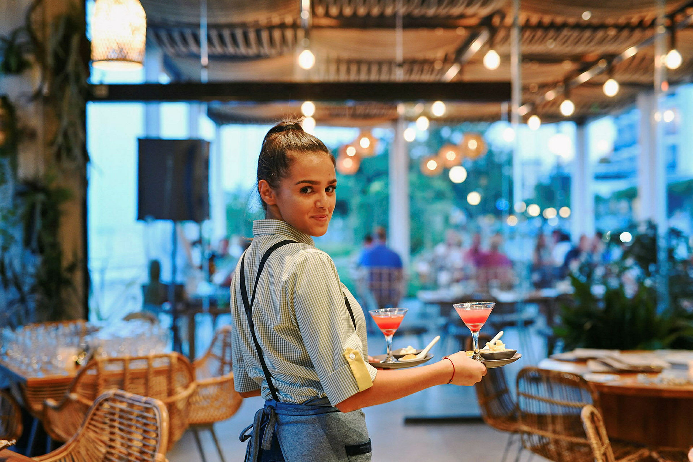Servitör som bär brickor med färgglada drinkar på en restaurang. (AI-genererad text)