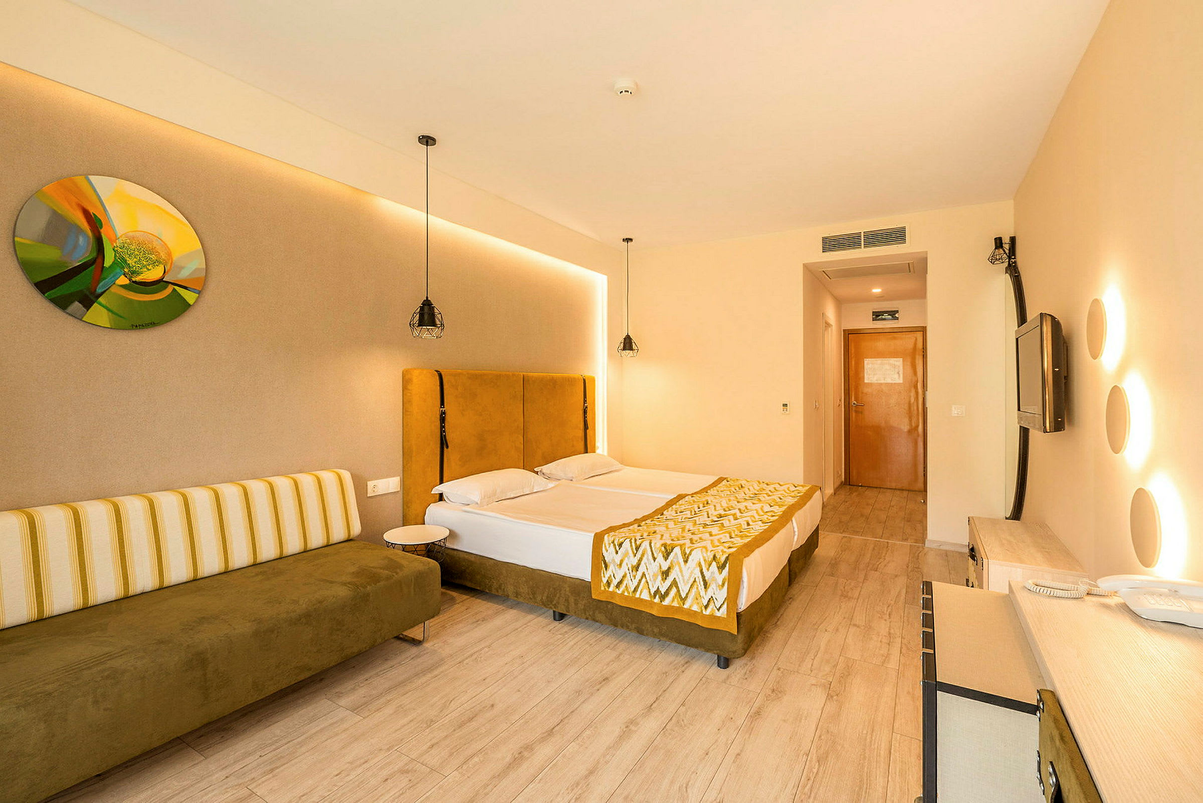 Ett hotellrum med två enkelsängar, en soffa och en dörr i bakgrunden. (AI-genererad text)