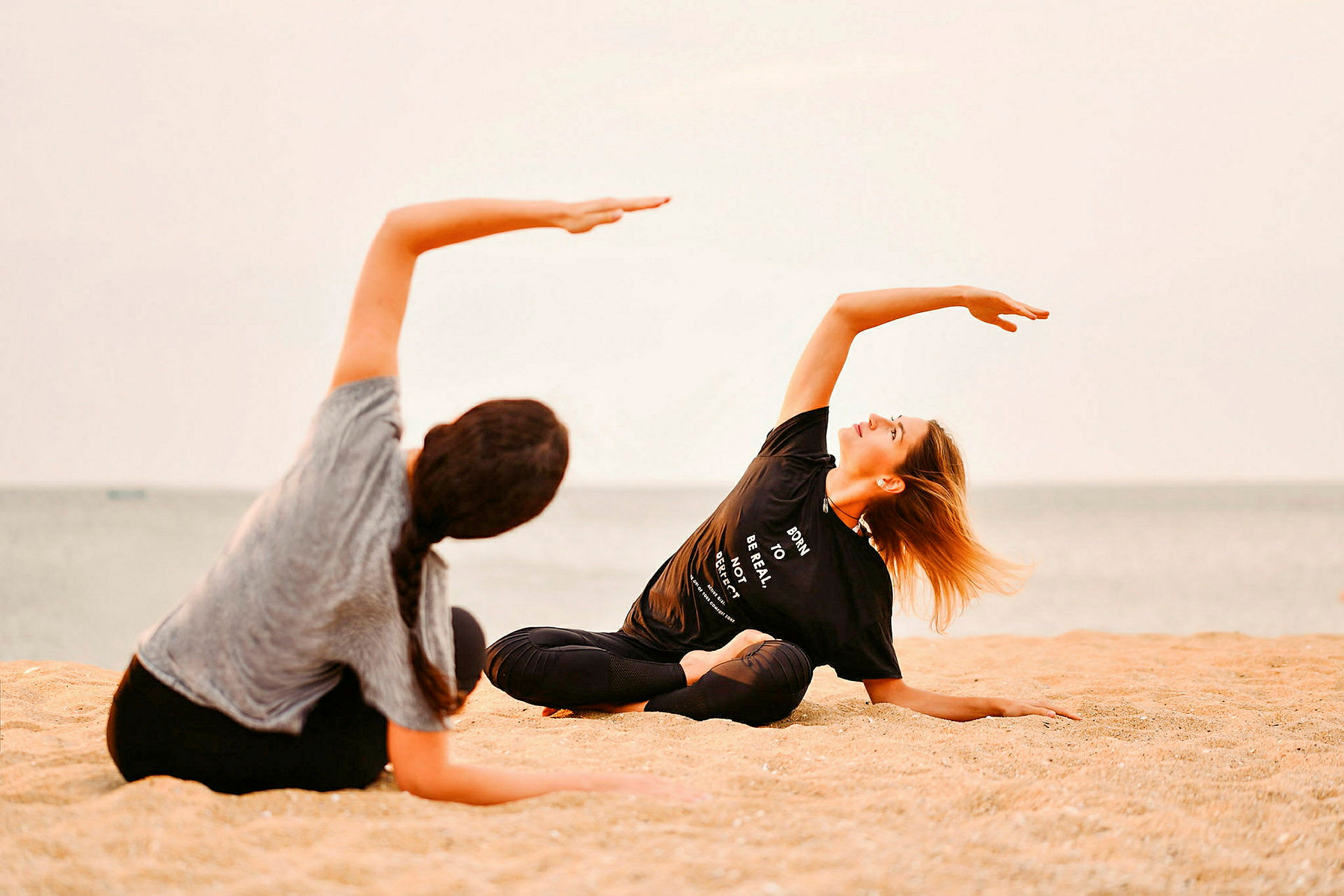 Två personer utövar yoga på en strand. (AI-genererad text)