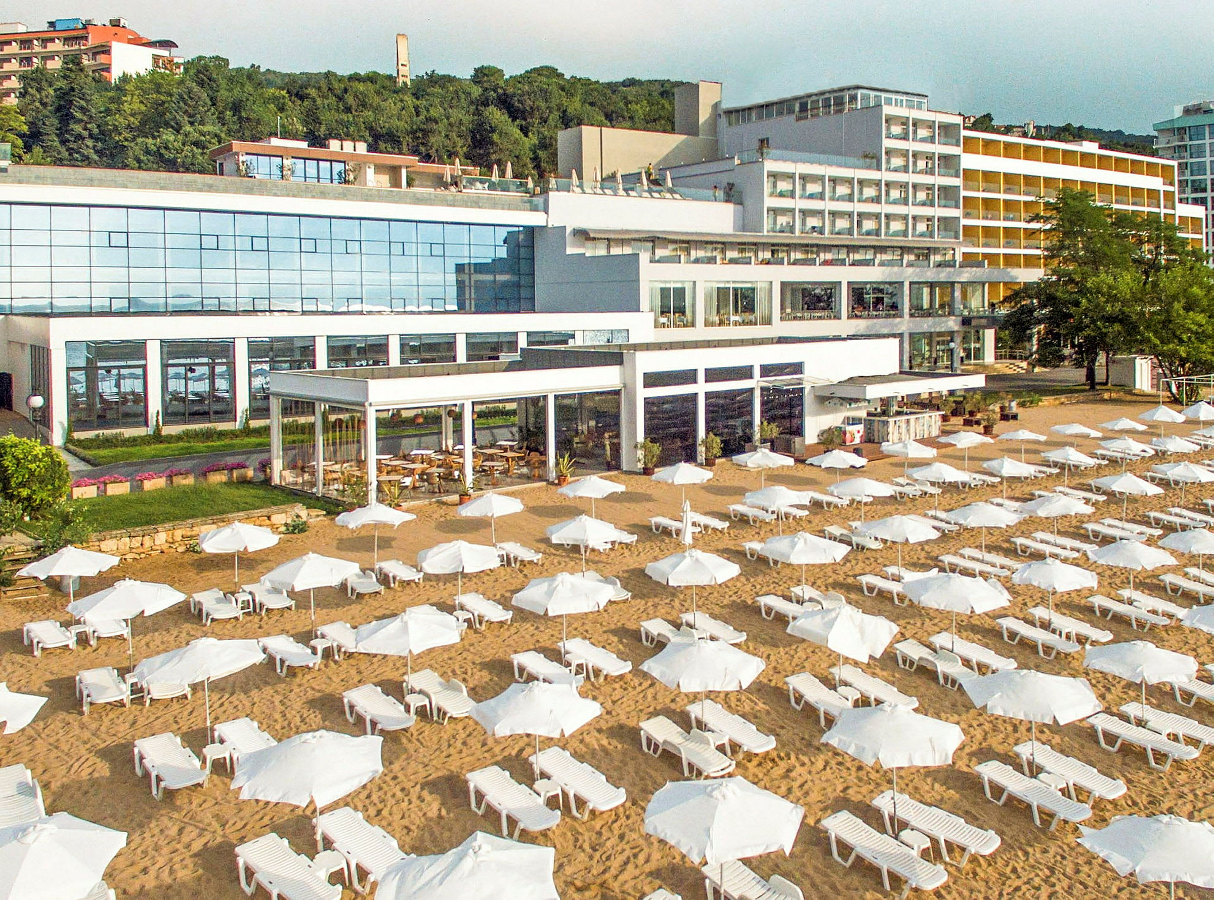 En strand med solstolar och parasoller framför ett stort hotell. (AI-genererad text)