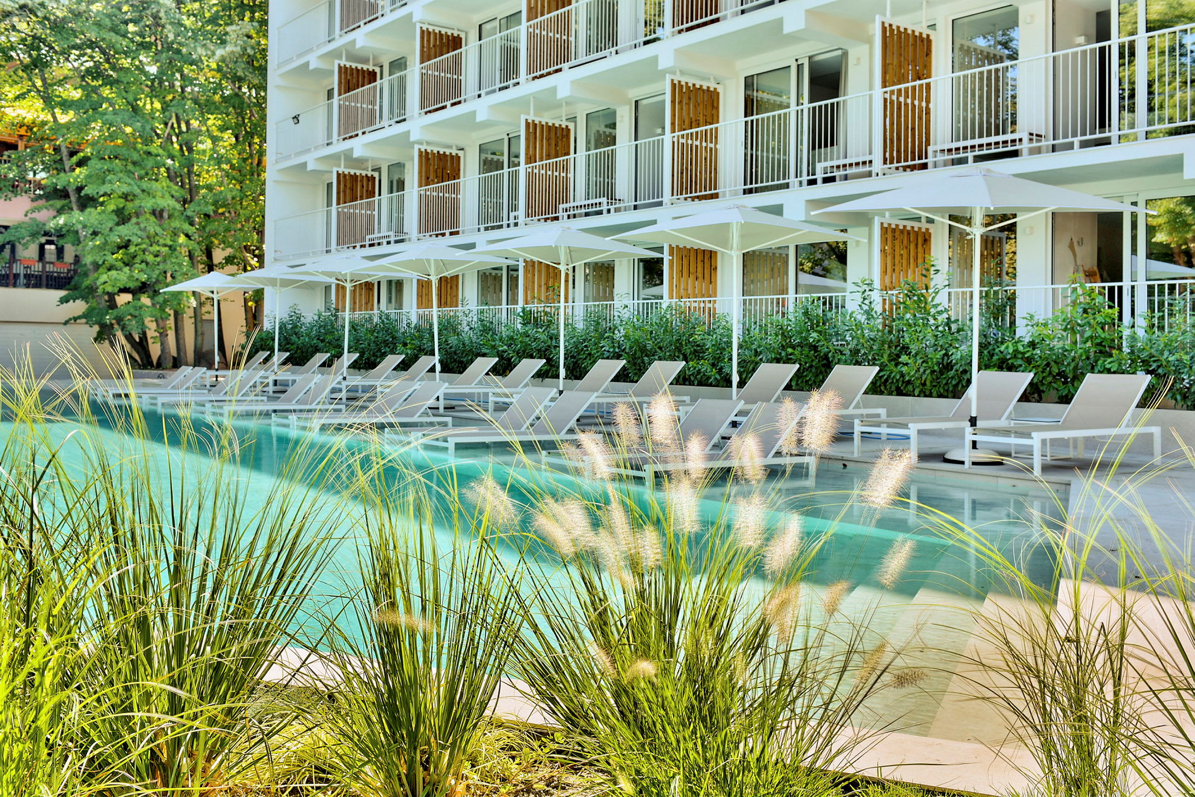 Exteriör av hotell med moderna balkonger samt solstolar vid en pool. (AI-genererad text)