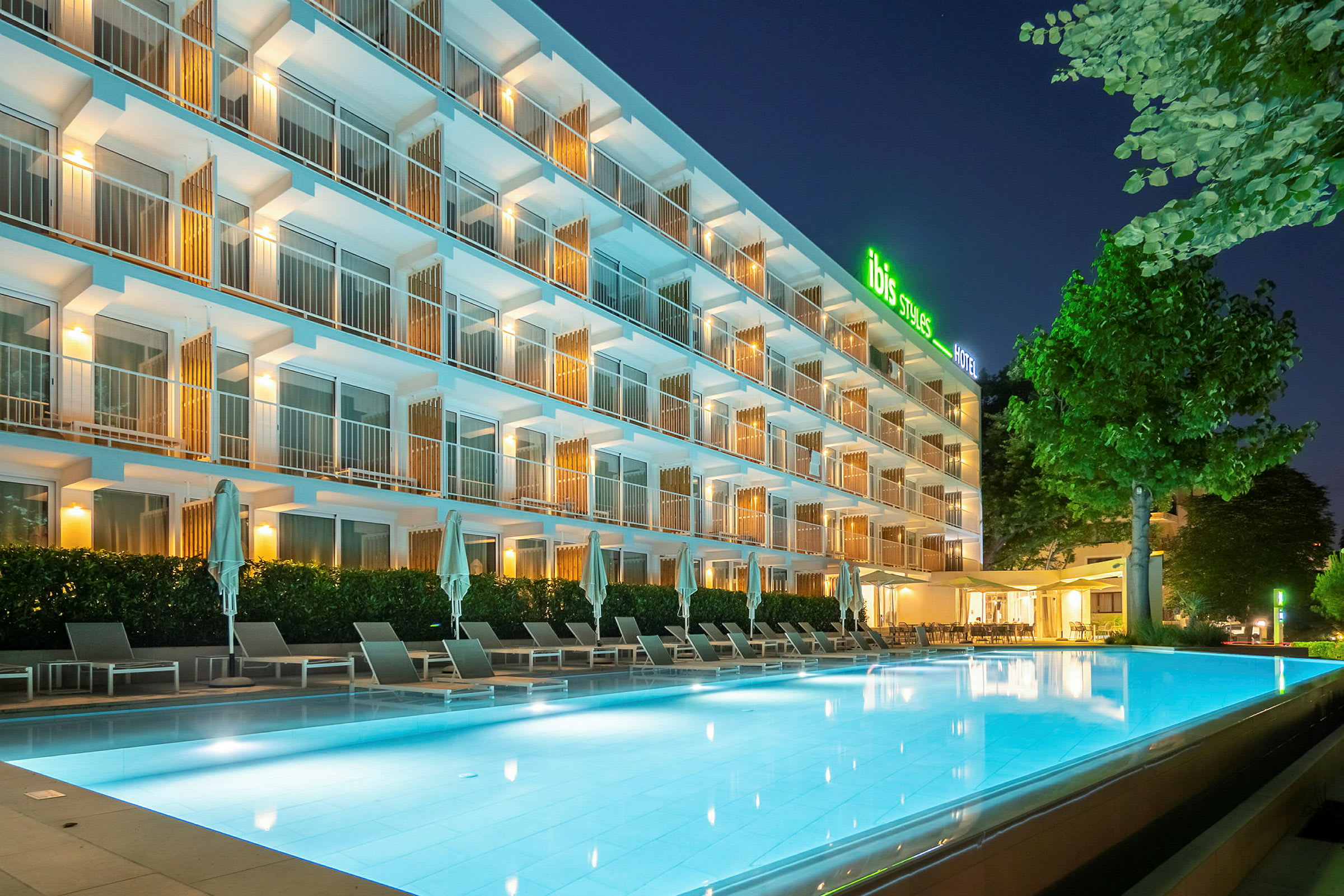 Hotell med utomhuspool i modernt upplyst nattmiljö. (AI-genererad text)