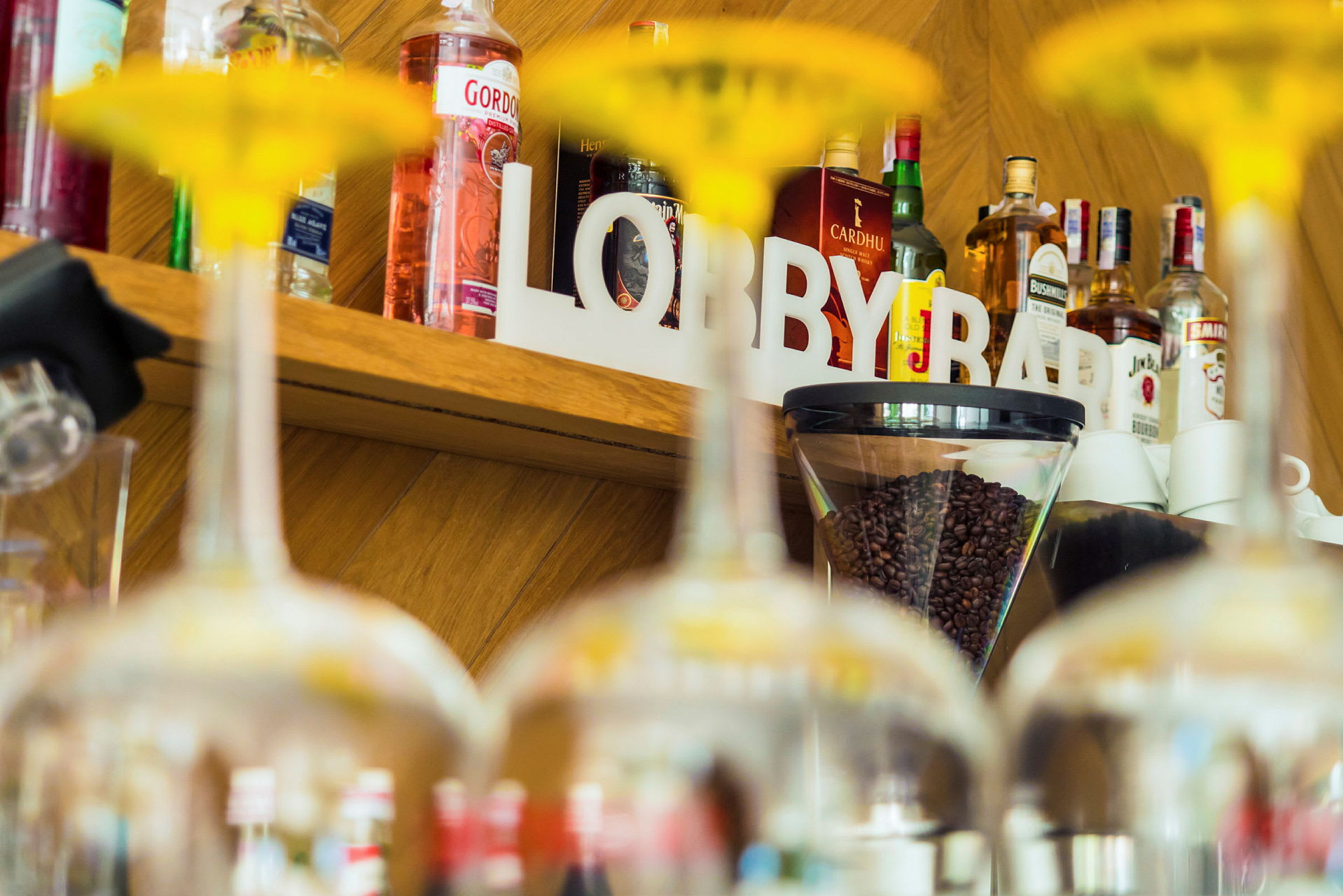 En hylla med flaskor, kaffebönor och texten 'LOBBY BAR' syns bakom glas. (AI-genererad text)