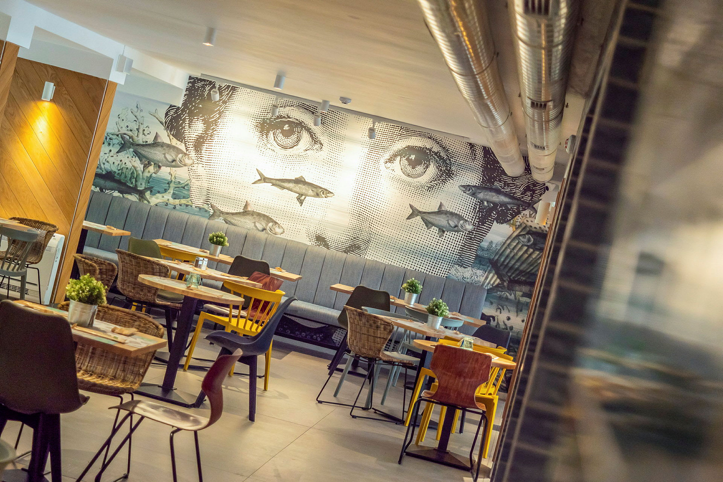 En restaurang med en väggdekor föreställande ett ansikte och fiskar. (AI-genererad text)
