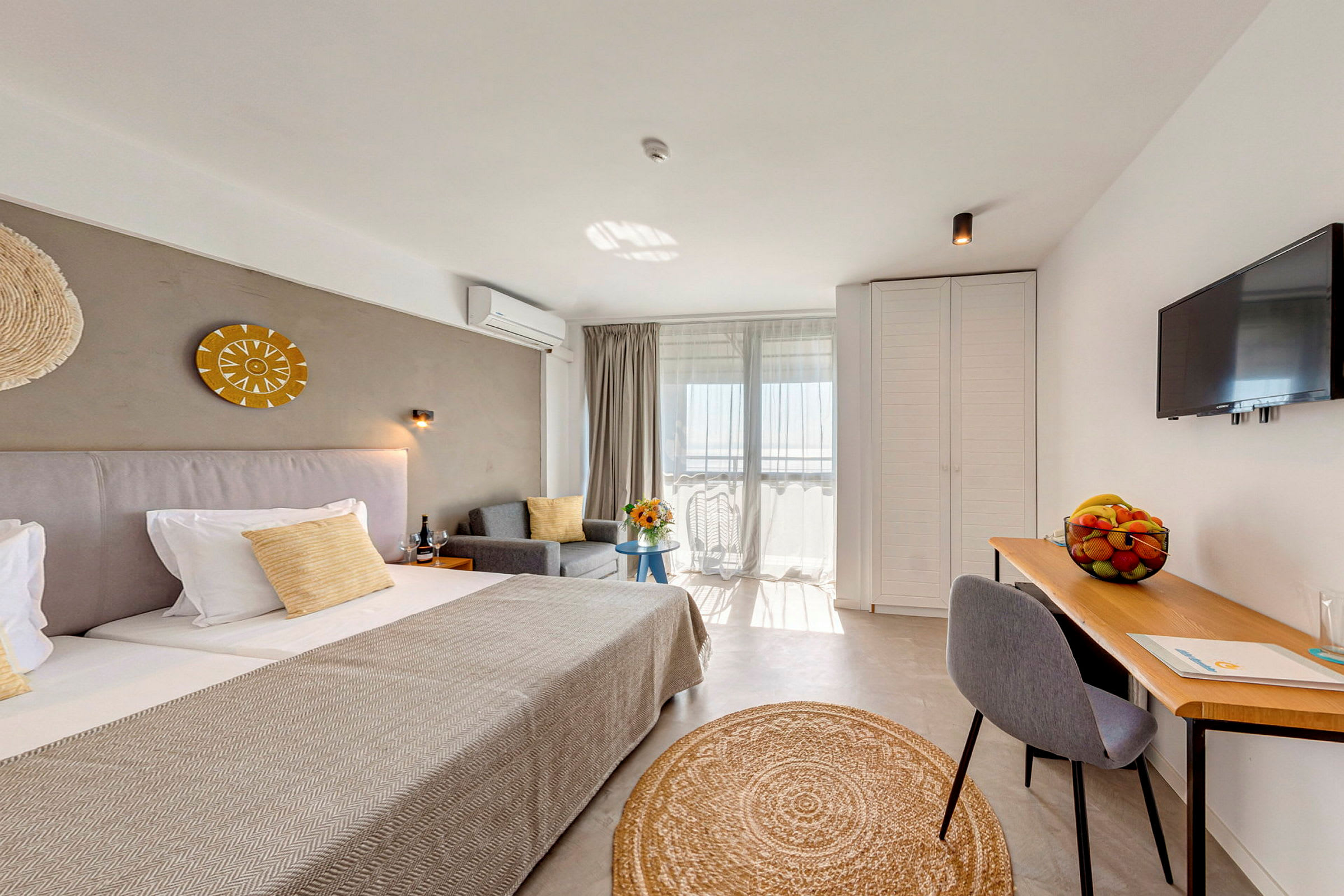Ett hotellrum med dubbelsäng, soffa, skrivbord och TV. (AI-genererad text)